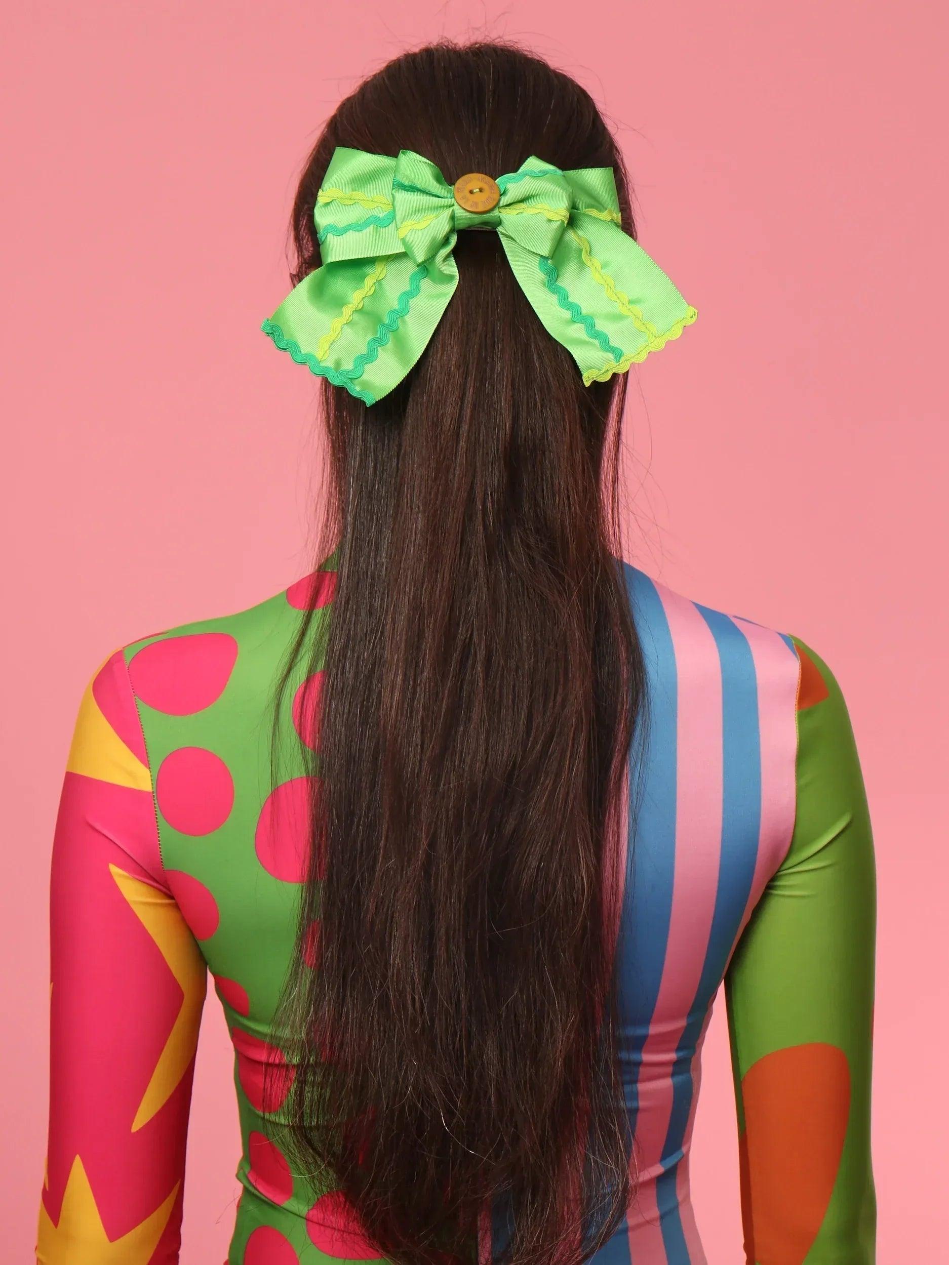 Pasador BEATRIZ con moño verde y botón, vista trasera en el cabello