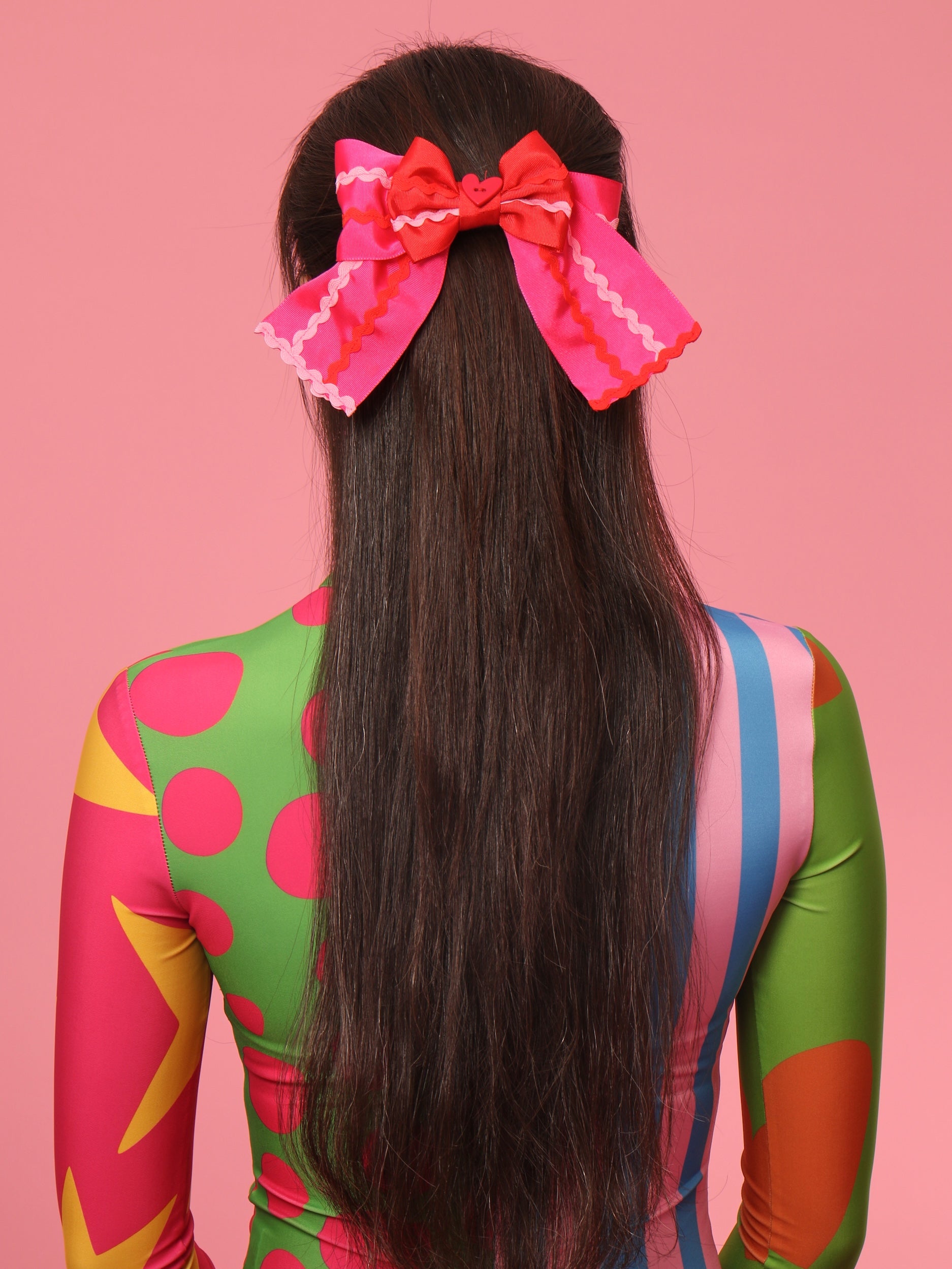 Pasador con lazo rojo y rosa en la parte trasera del cabello oscuro