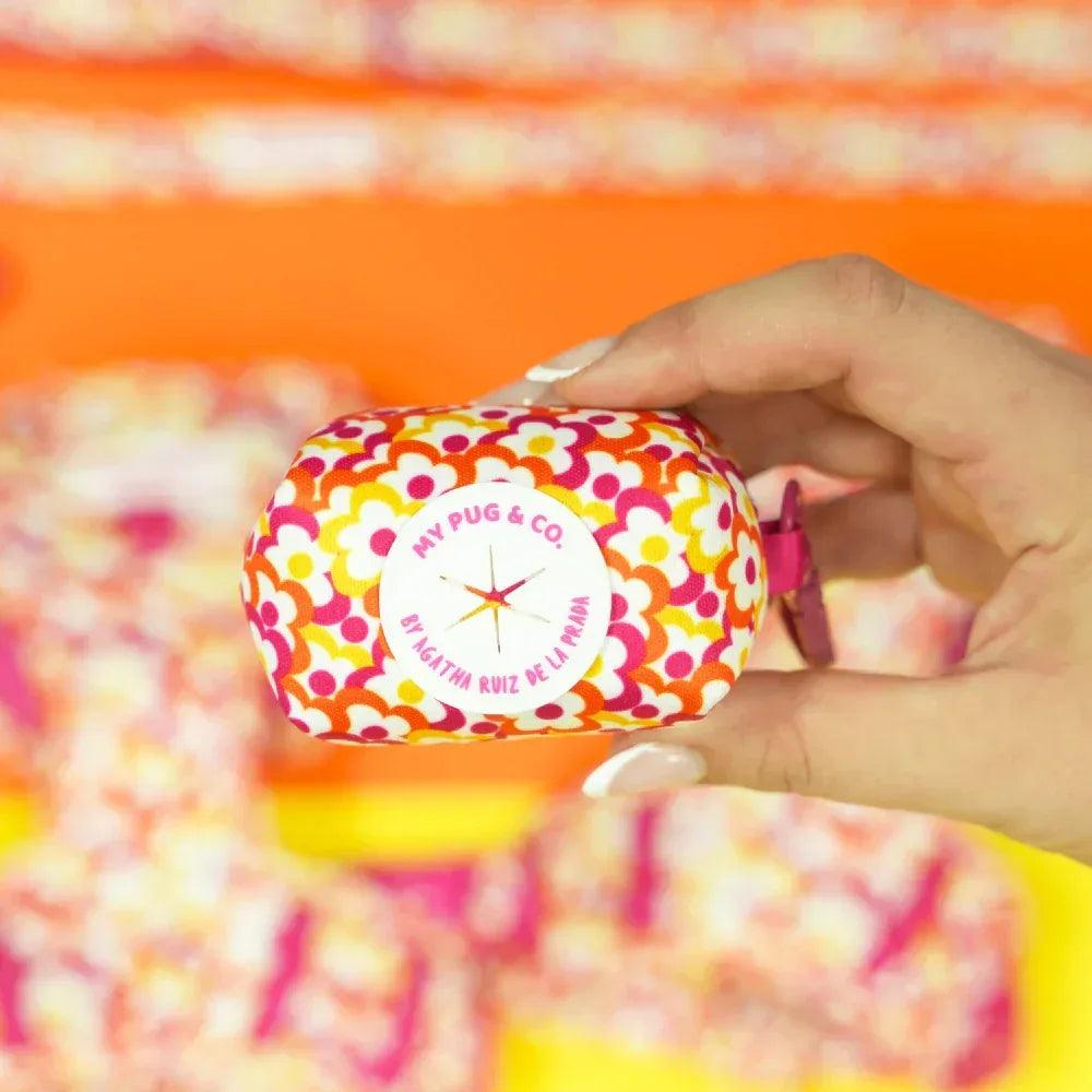 Porta bolsas de tela floral pop con logo circular y cierre tipo broche