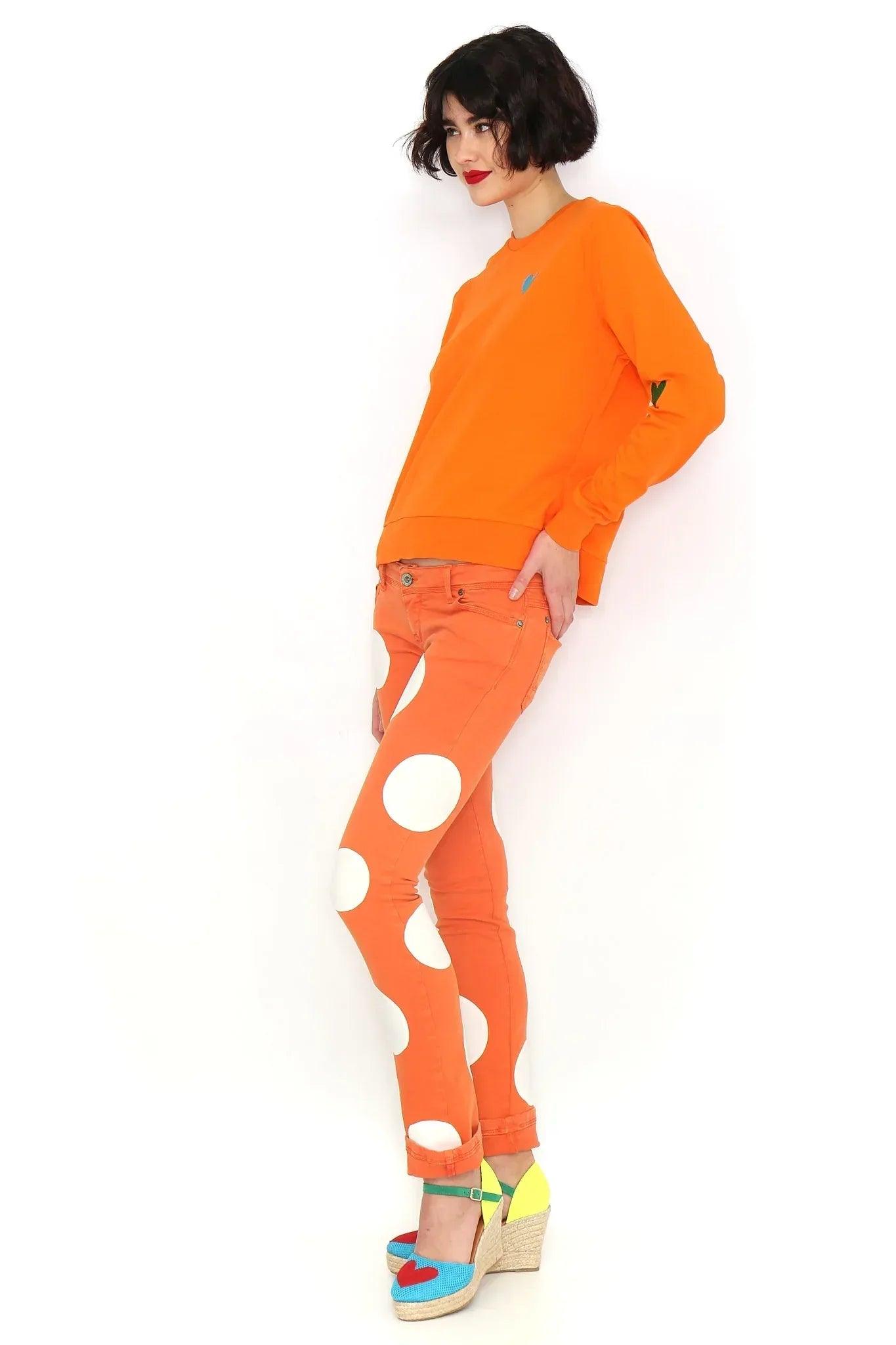 Sudadera naranja básica con corazón azul bordado y detalle en el puño de la manga.