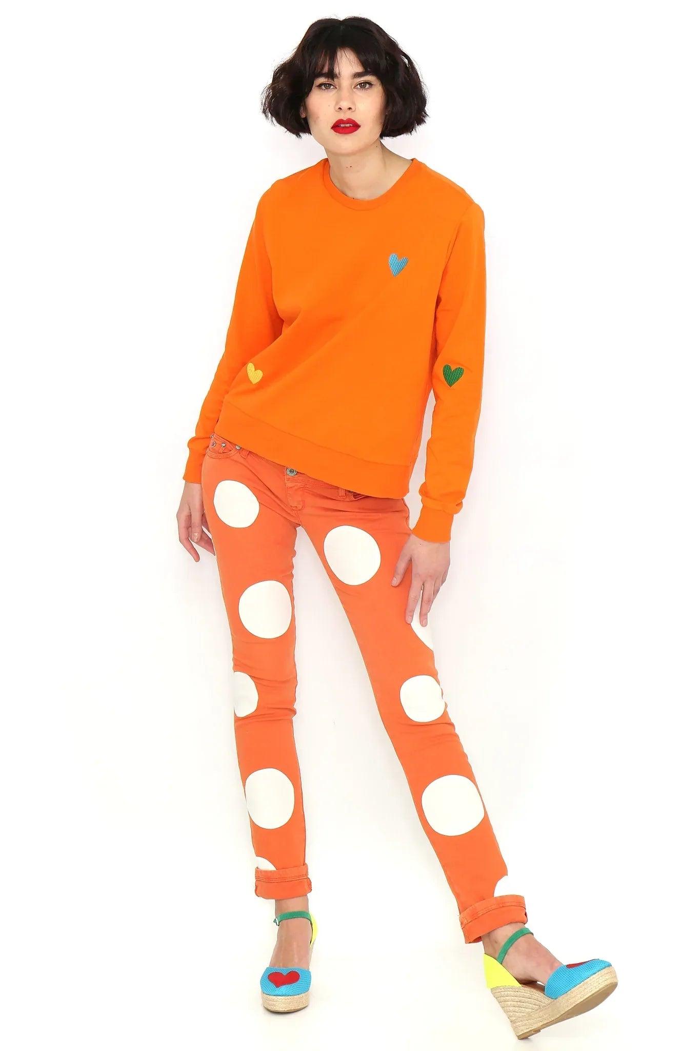 Sudadera naranja básica con corazón azul en el pecho y mangas largas con puños.