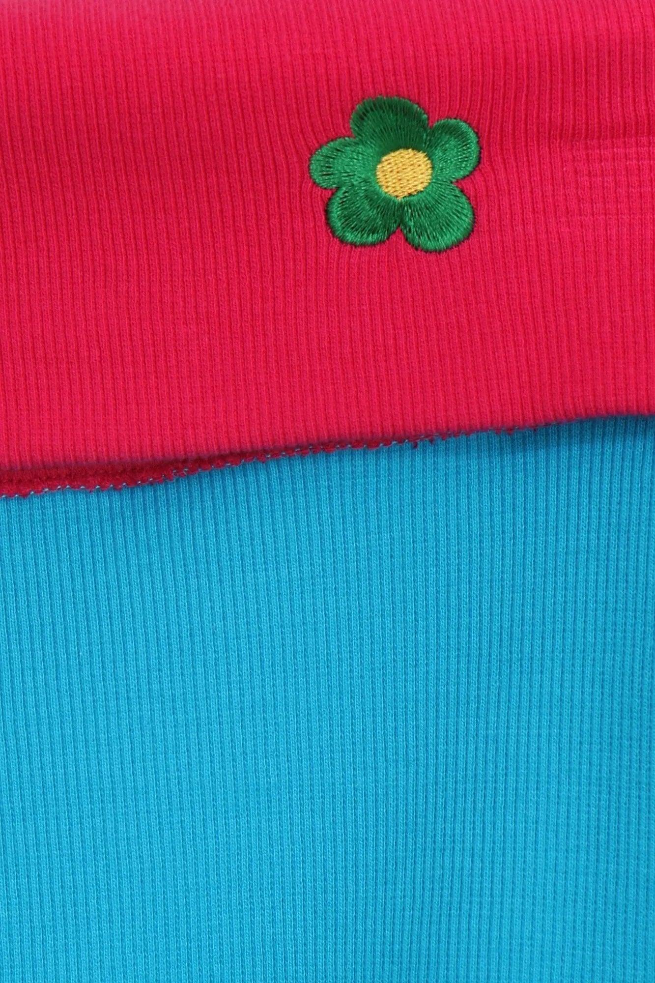 Detalle de camiseta: punto acanalado fucsia con flor verde y centro amarillo
