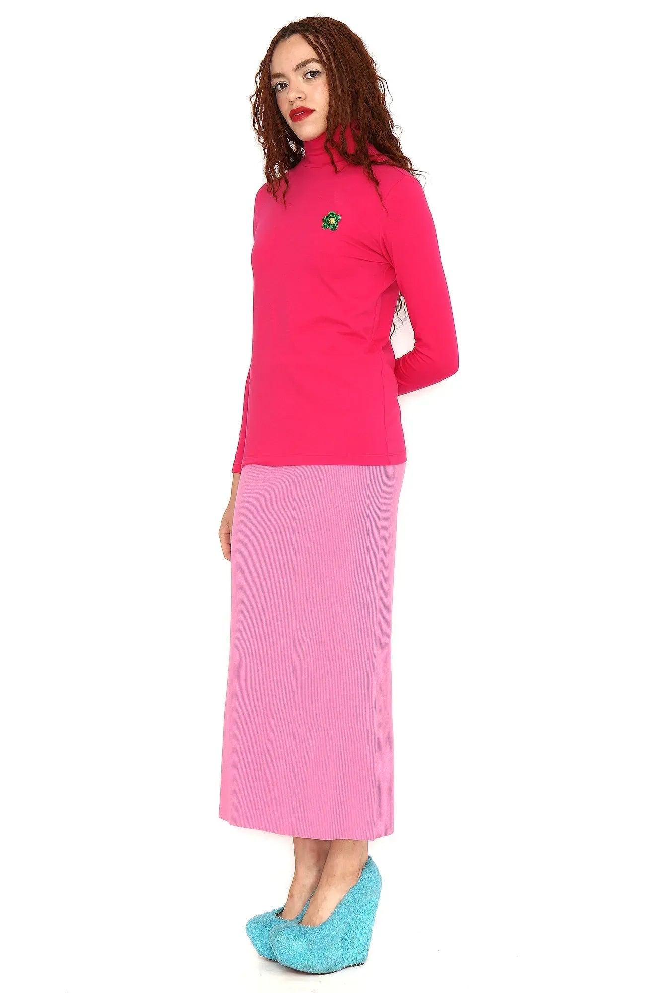 Conjunto camiseta fucsia con cuello alto y flor verde, con falda lila larga