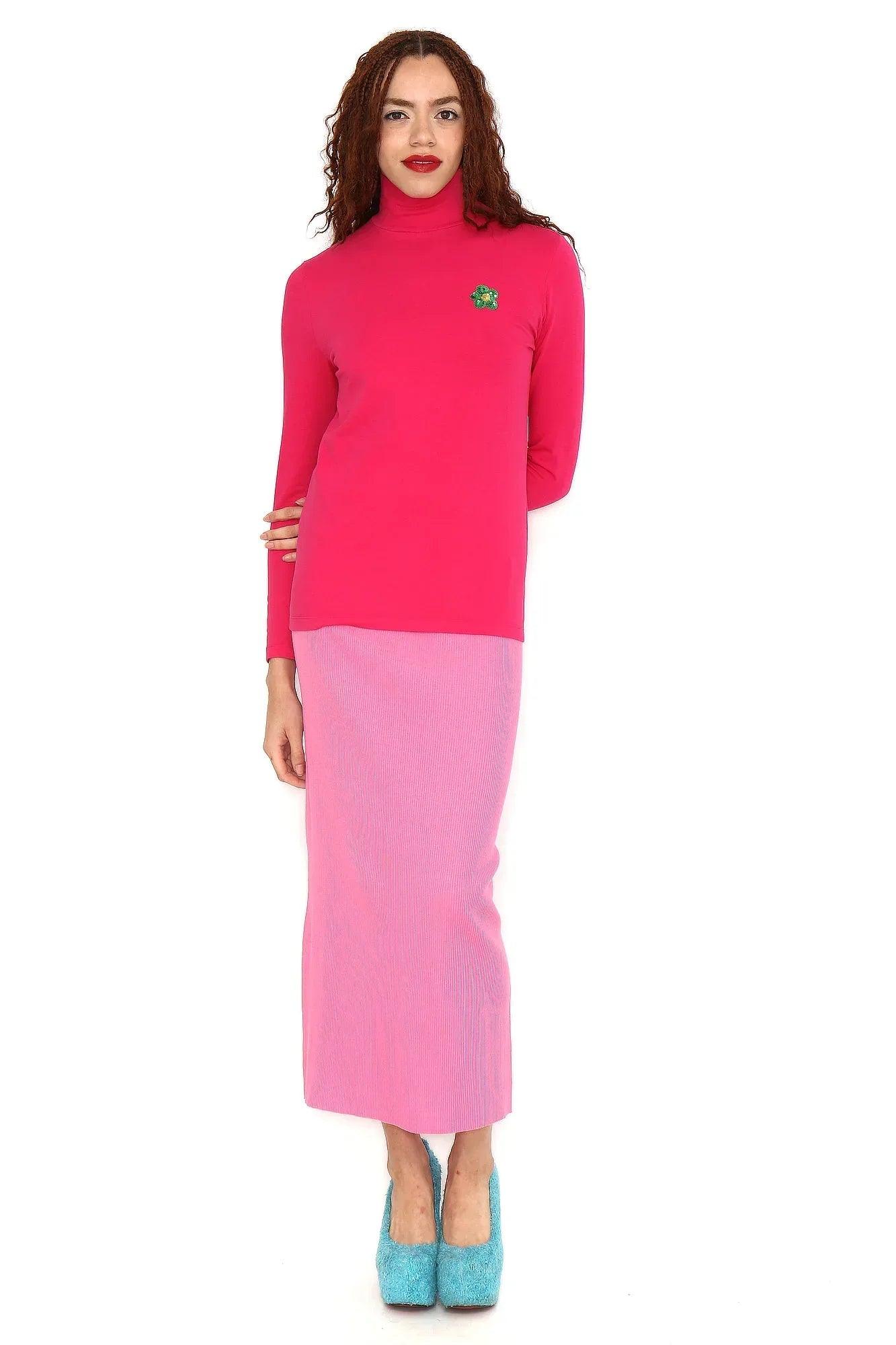 Conjunto camiseta fucsia con cuello alto y flor verde, con falda lila midi