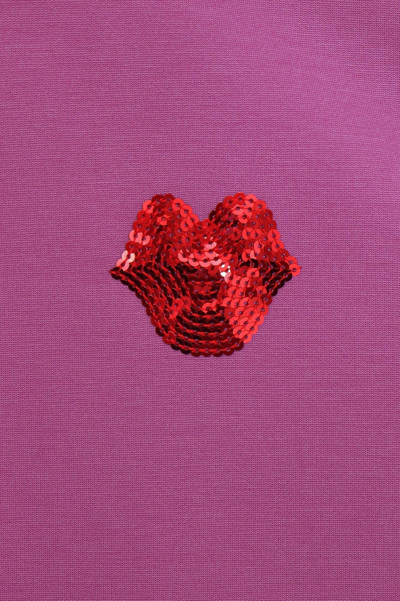 Corazón rojo con lentejuelas en el pecho de un polo morado