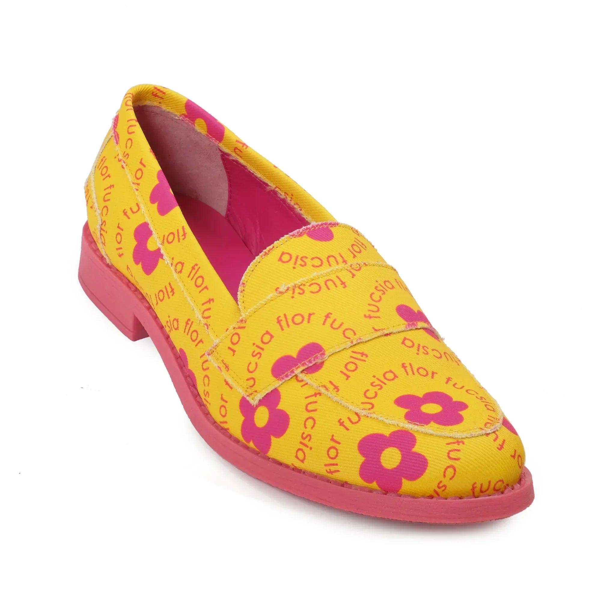 Mocasín amarillo con flores moradas, costura visible y tacón bajo rosa.