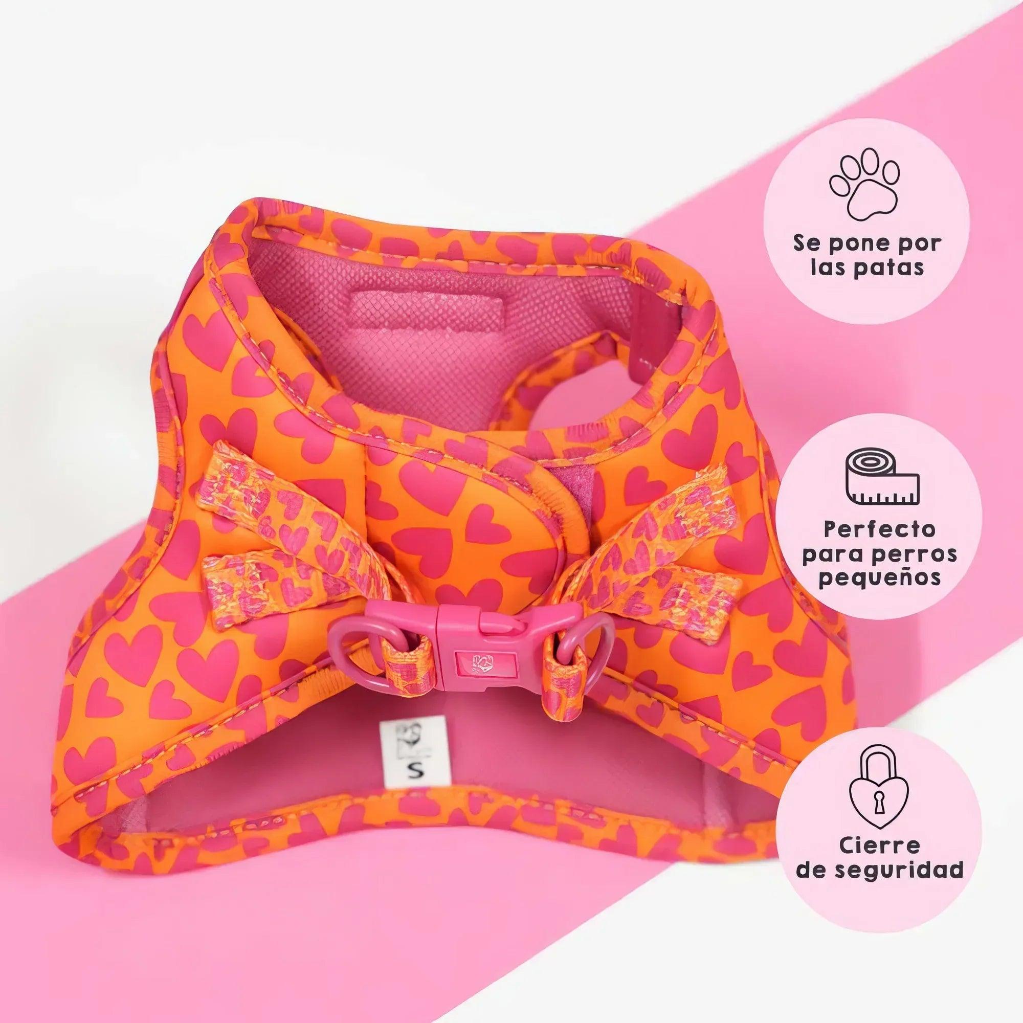 Arnés ajustable con corazones rosa y naranja, correa cruzada y cierre frontal.