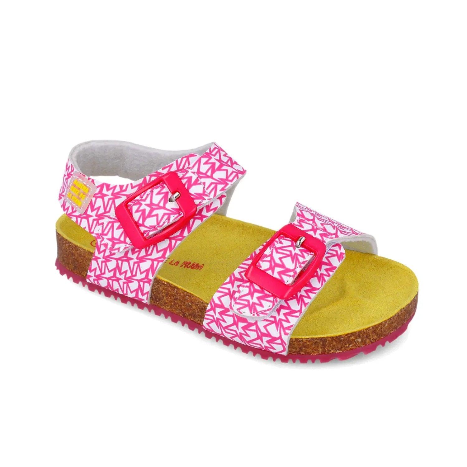 Sandalias fucsia con hebilla roja sobre tira cruzada y suela de corcho y base amarilla.