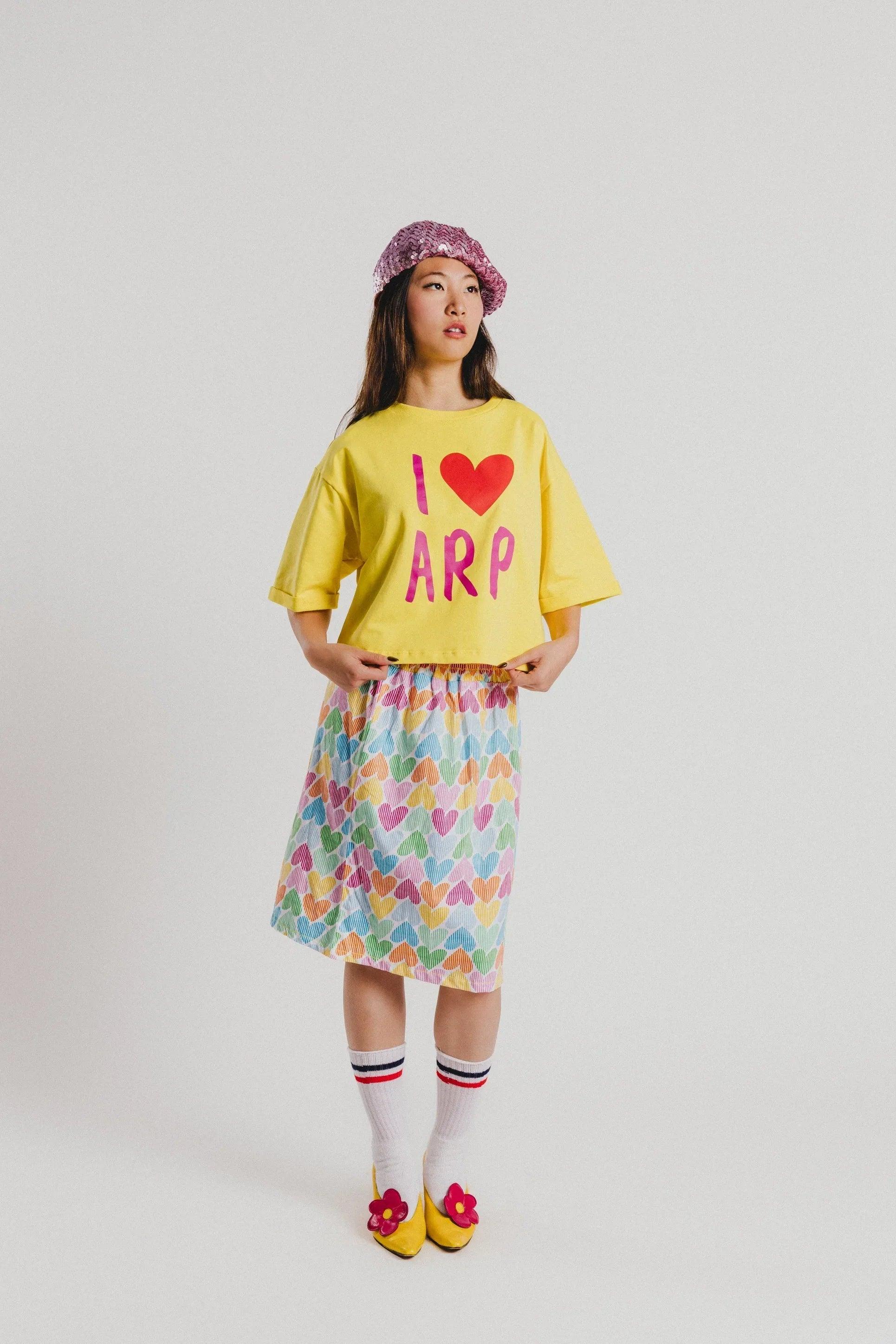 Camiseta amarilla con corazón rojo y letras ARP rosa, manga corta, vista de frente