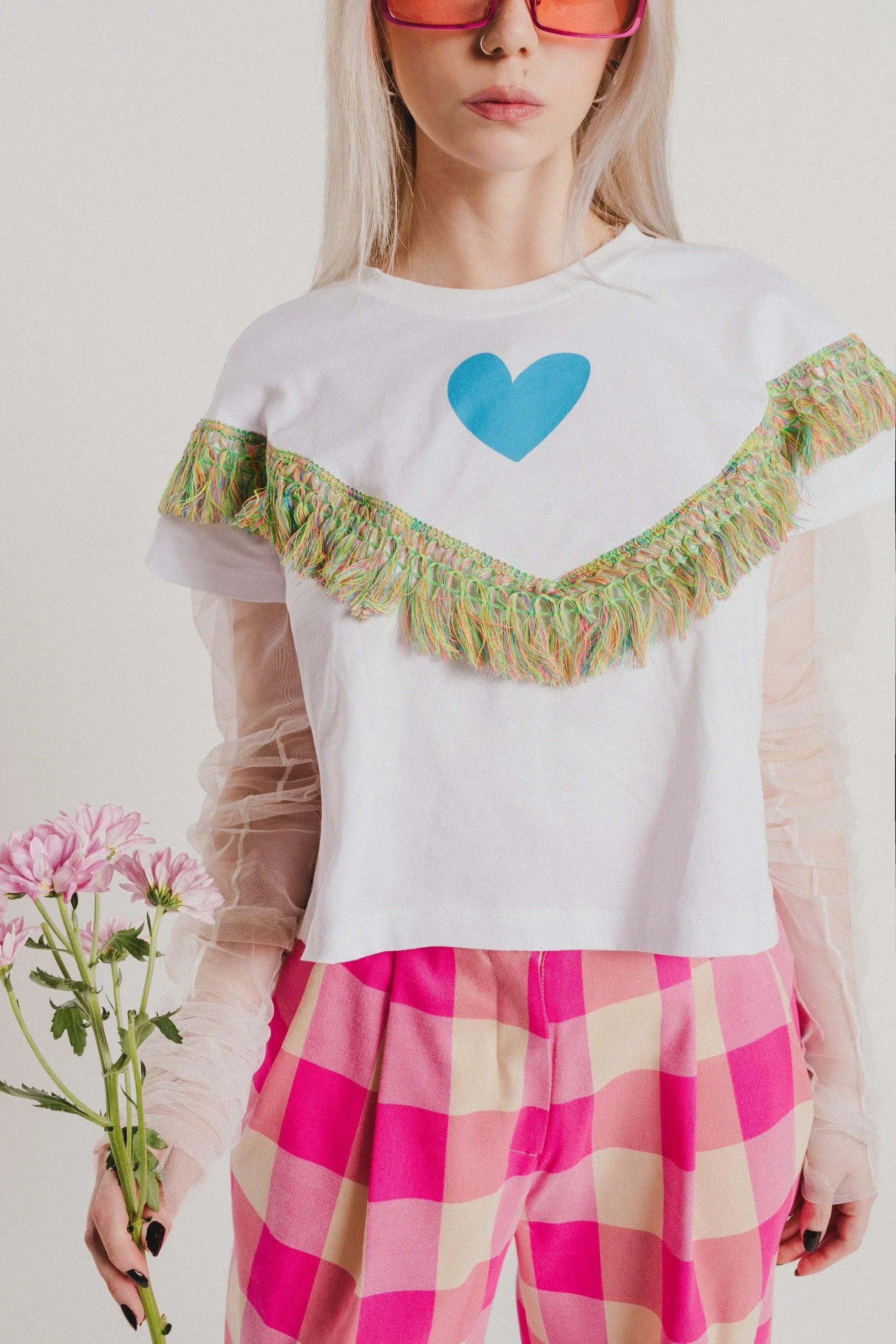 Camiseta blanca con corazón azul y flecos verde-dorados en el hombro