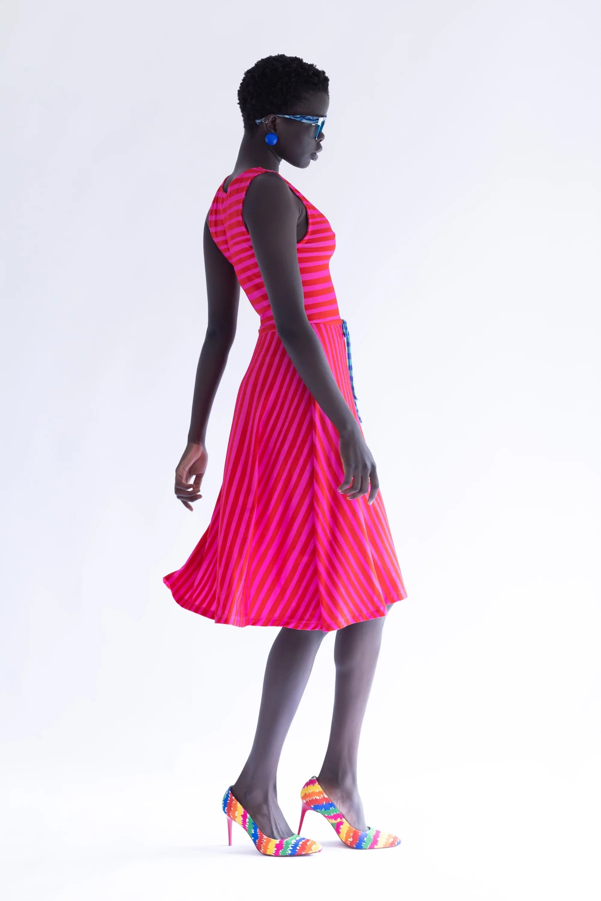 Vestido sin mangas rayado fucsia y rojo, falda con vuelo y lazo en la cintura.