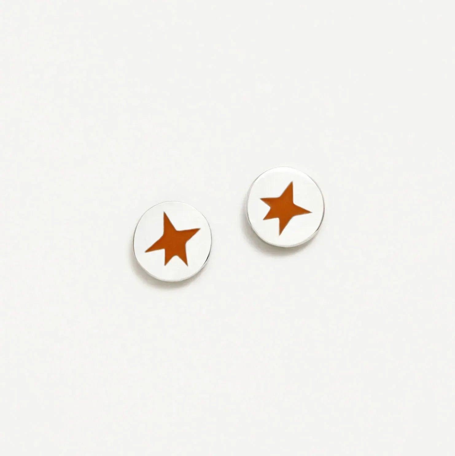 Par de pendientes redondos blancos con estrella naranja, vista frontal
