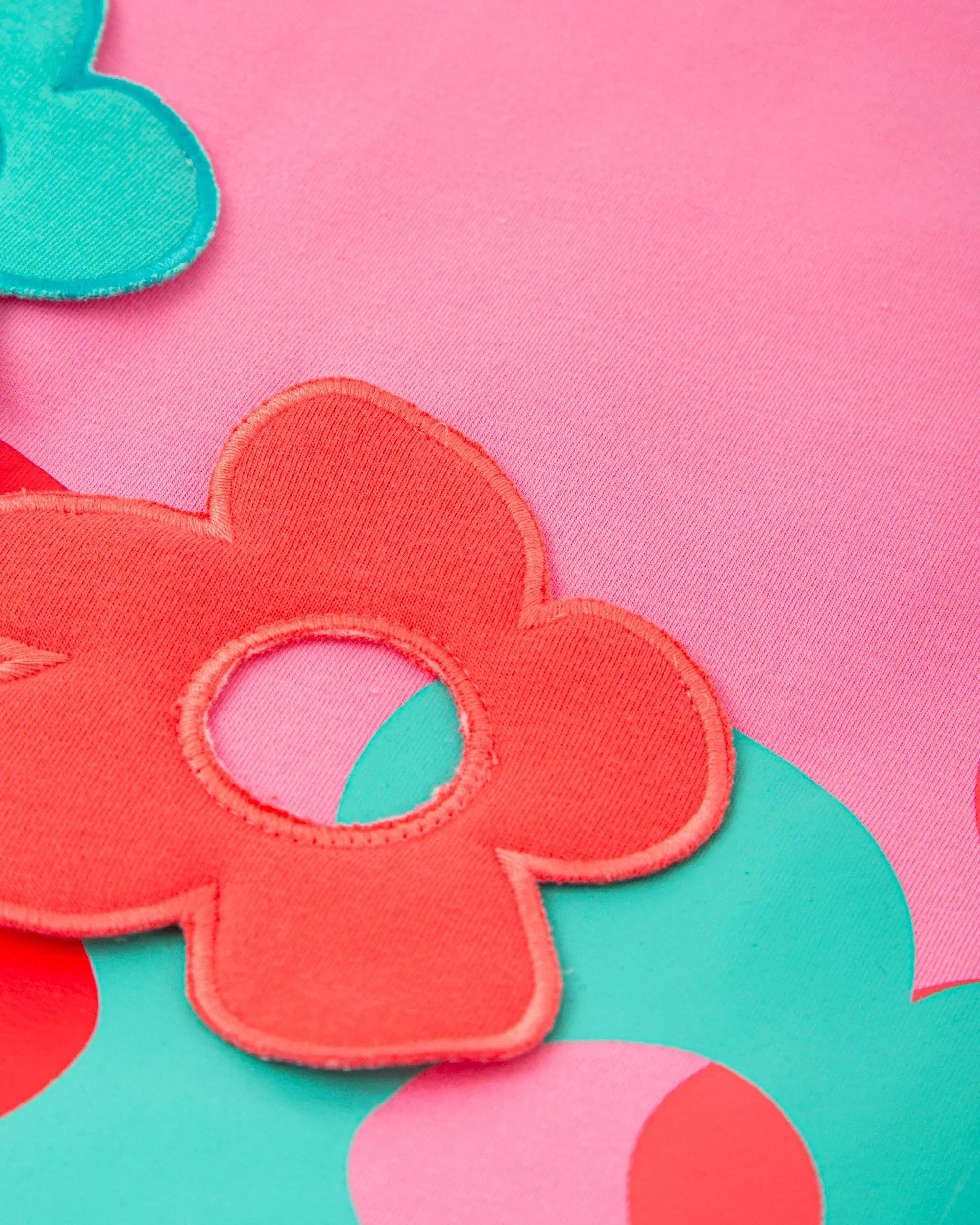Aplicación de flores de colores en vestido fucsia, detalle de tela