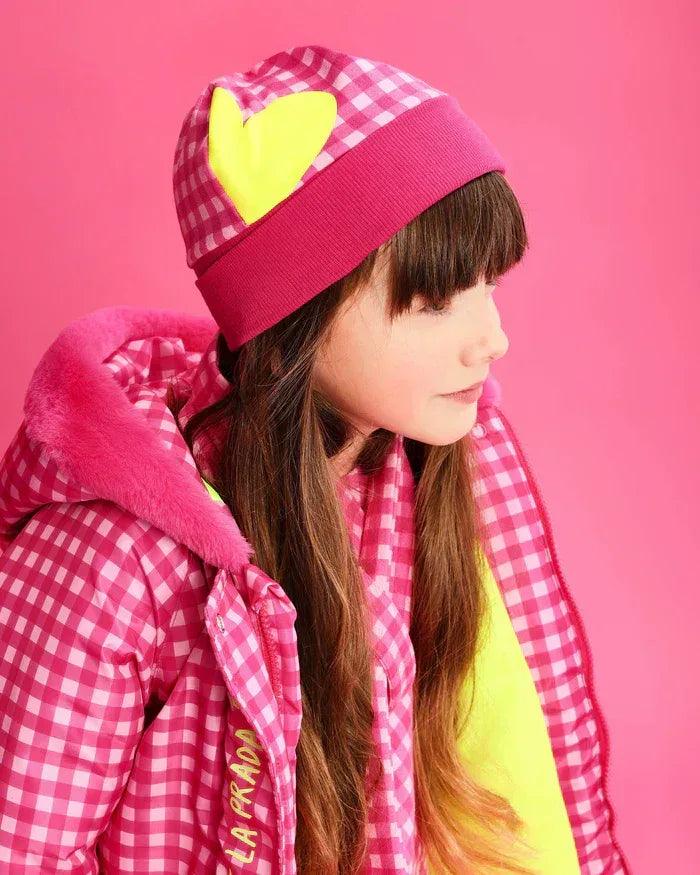 Gorro fucsia de cuadros y bufanda a juego con corazón amarillo, alrededor del cuello