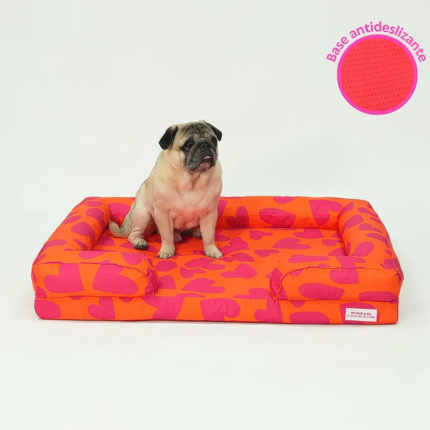 Cama acolchada para mascotas con patrón de corazones naranja y fucsia, base antideslizante
