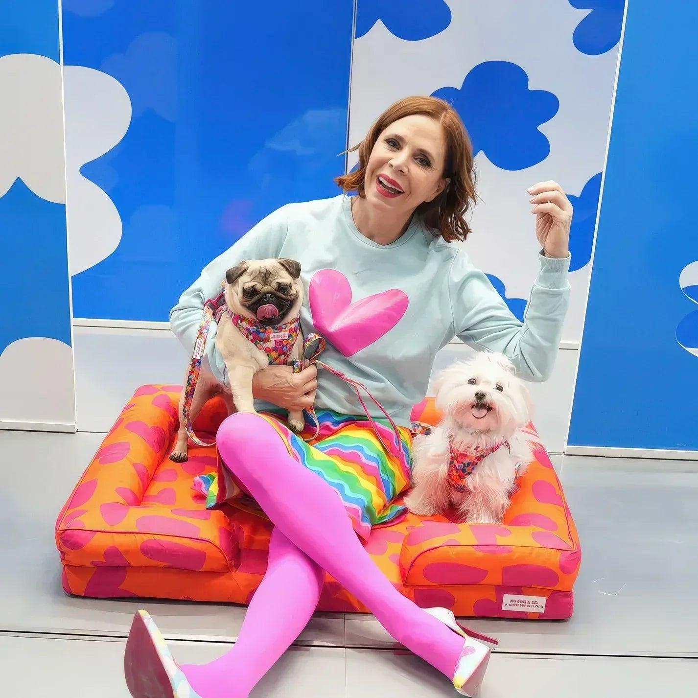 Cama acolchada para mascotas con patrón de corazones naranja y fucsia, dos perros