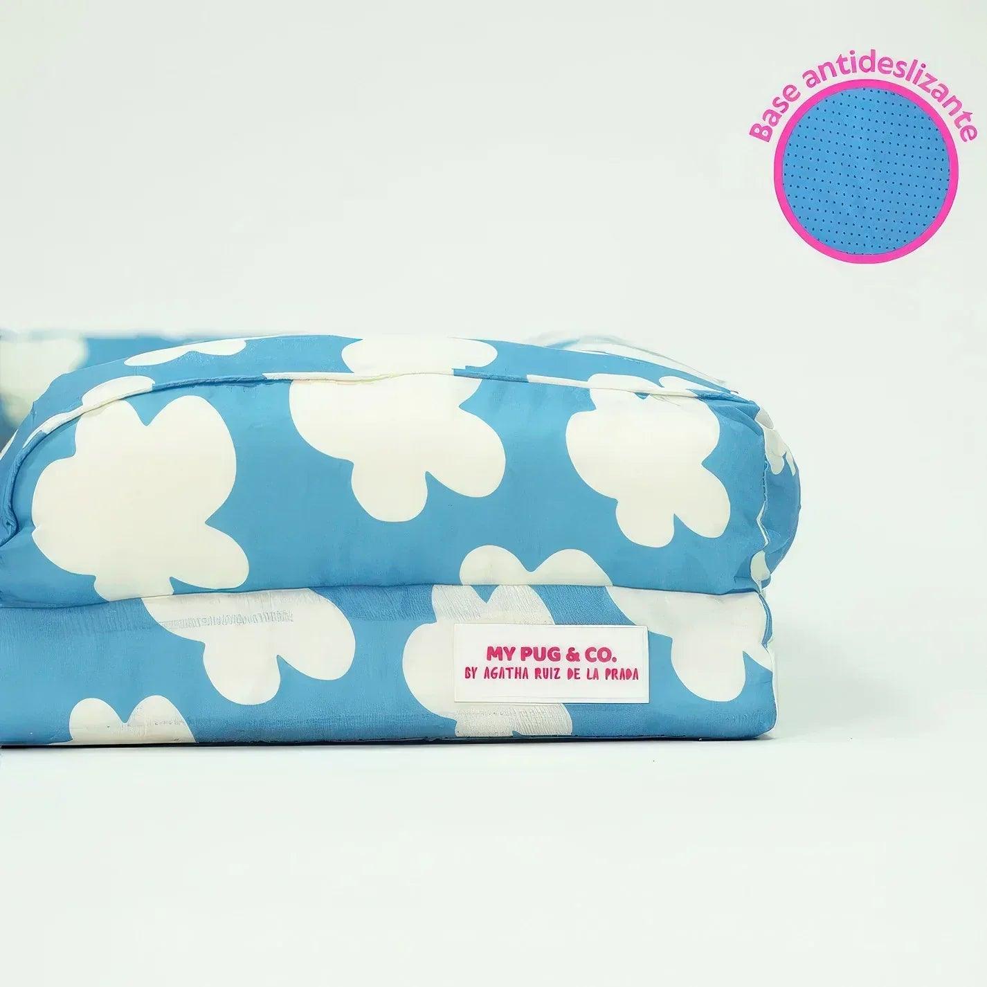 Cama acolchada para mascotas azul enrollada con estampado de flores blancas