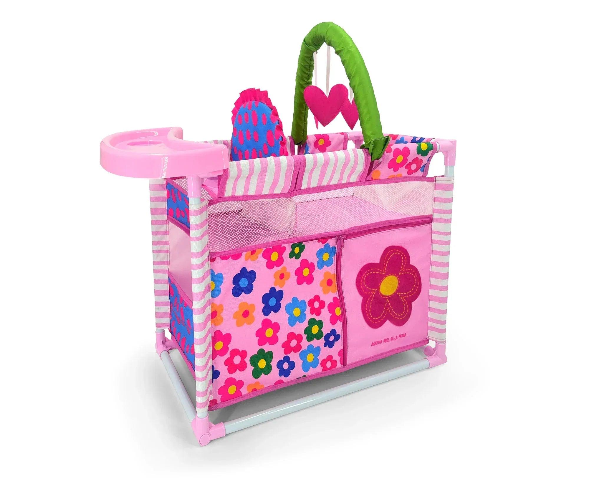 Cuna cambiadora plegable rosa con asa verde y estampado de flores coloridas