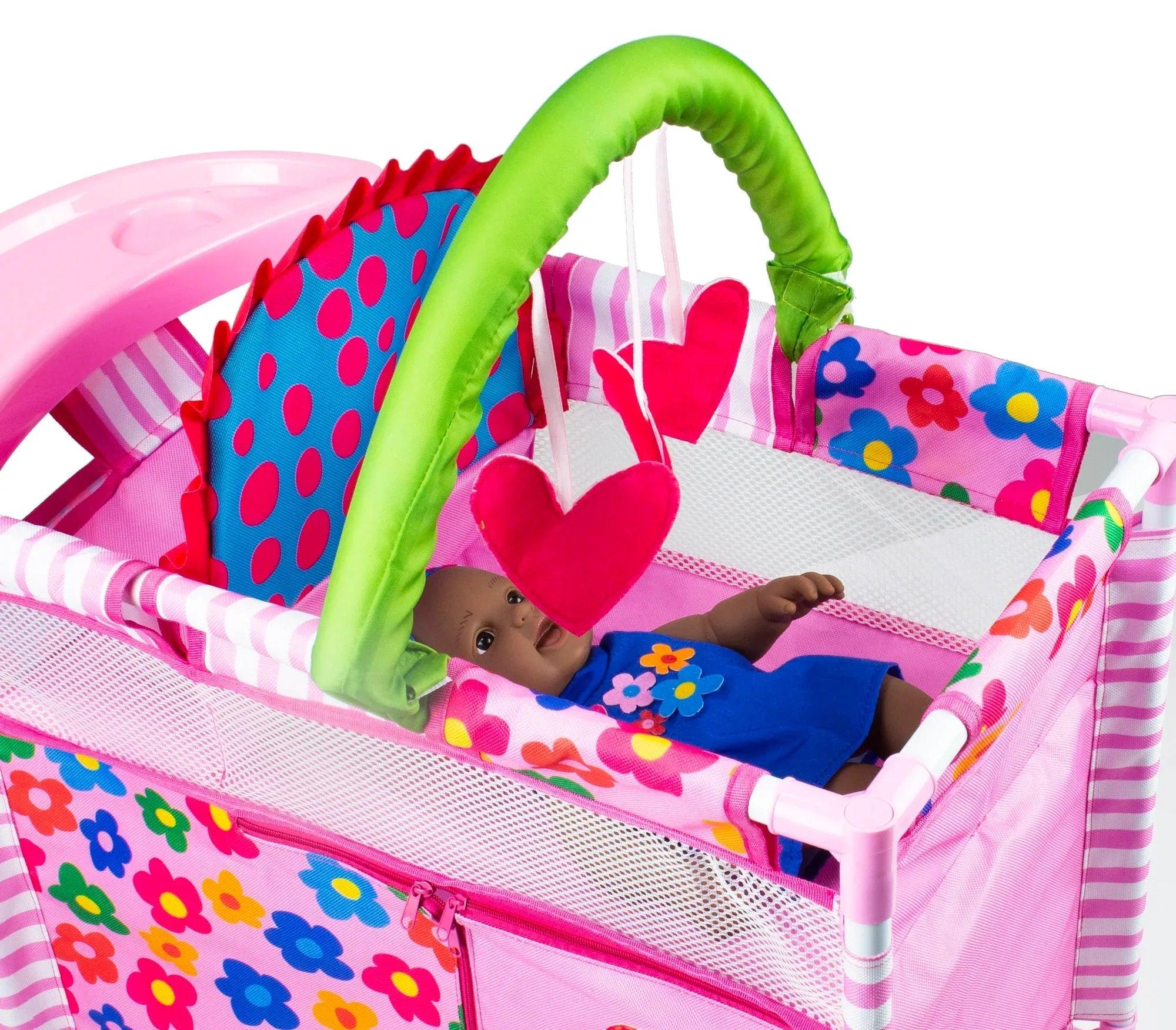 Cuna cambiadora rosa con asa verde, corazón rojo y funda estampada multicolor