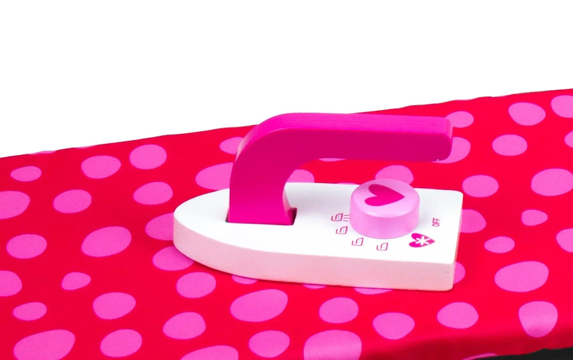 Plancha de juguete rosa con base blanca sobre tela de lunares