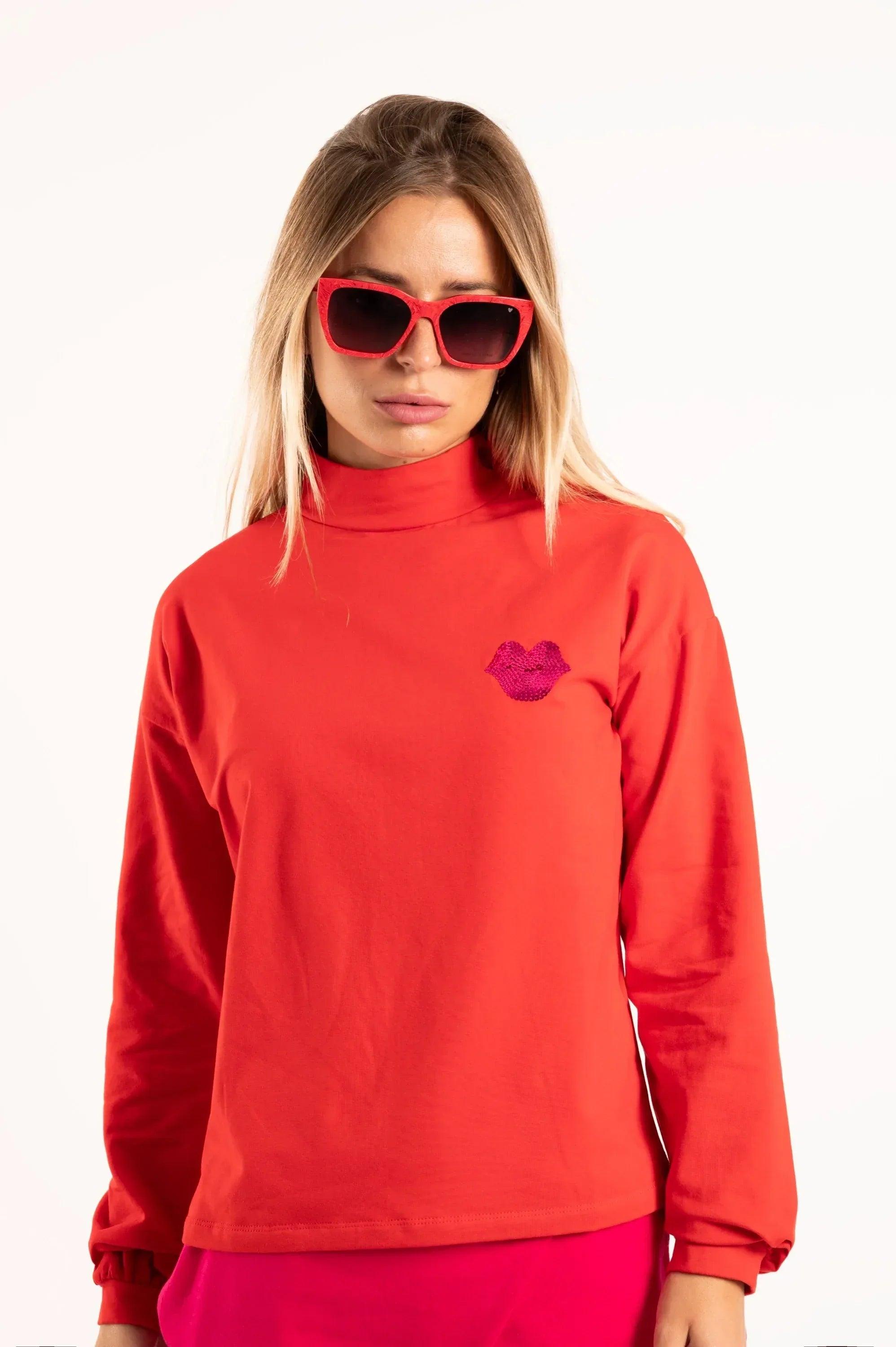 Camiseta roja de cuello alto y manga larga, con corazón de lentejuelas rosas en el pecho