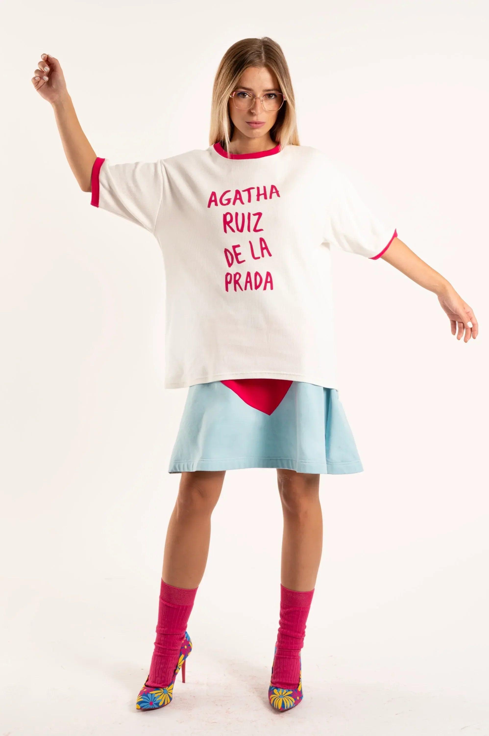 Camiseta blanca con cuello y puños fucsia, y letras fucsias frontales.