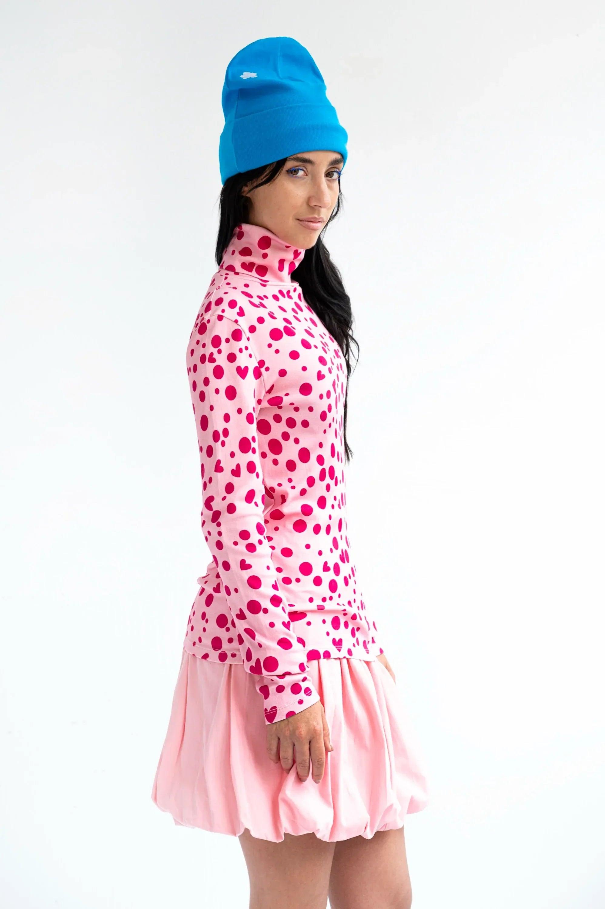 Camiseta de cuello alto rosa con corazones y topos, manga larga y volante en bajo.