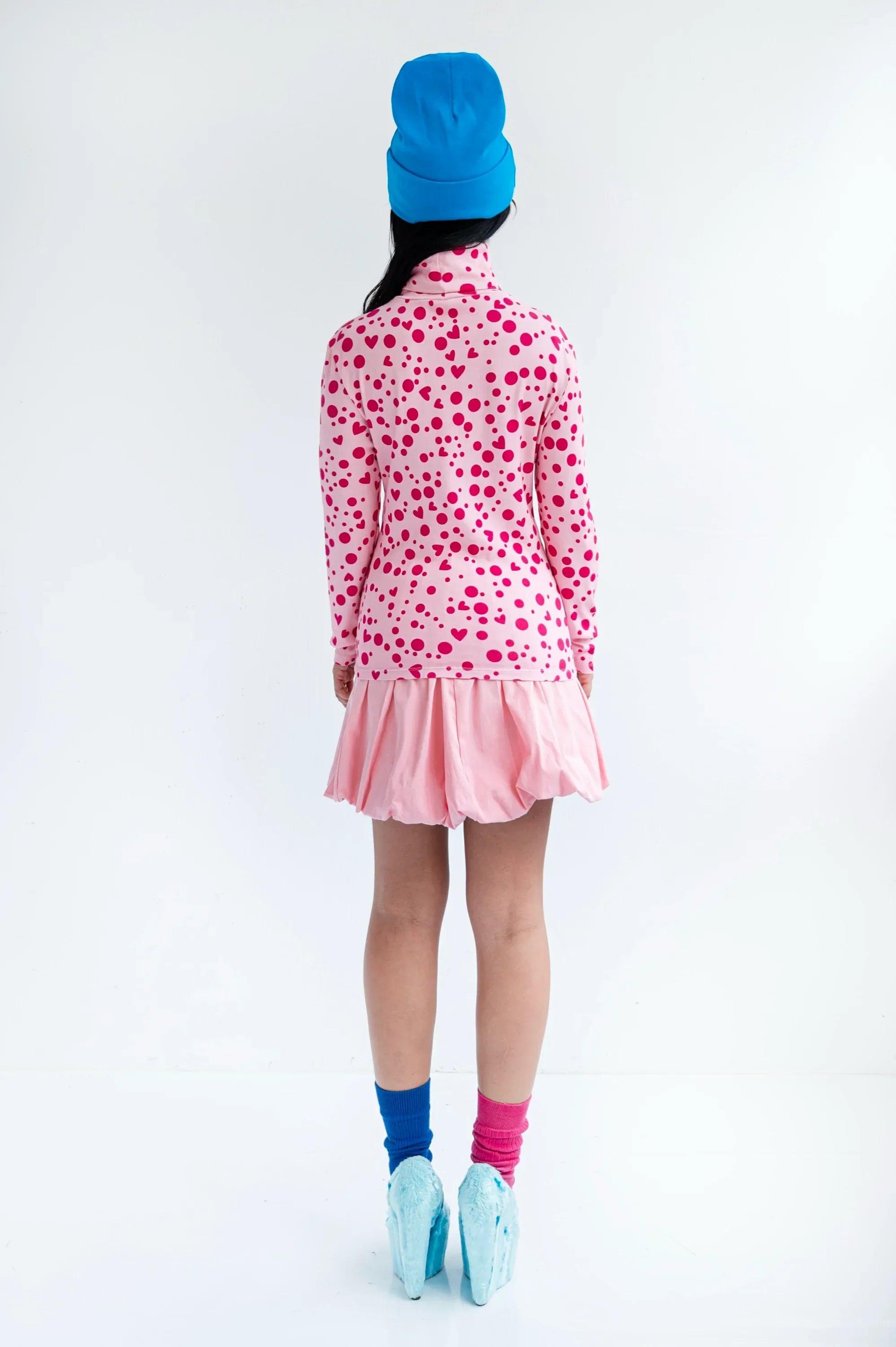 Camiseta de cuello alto rosa con corazones y topos, vista trasera y bajo con volante.
