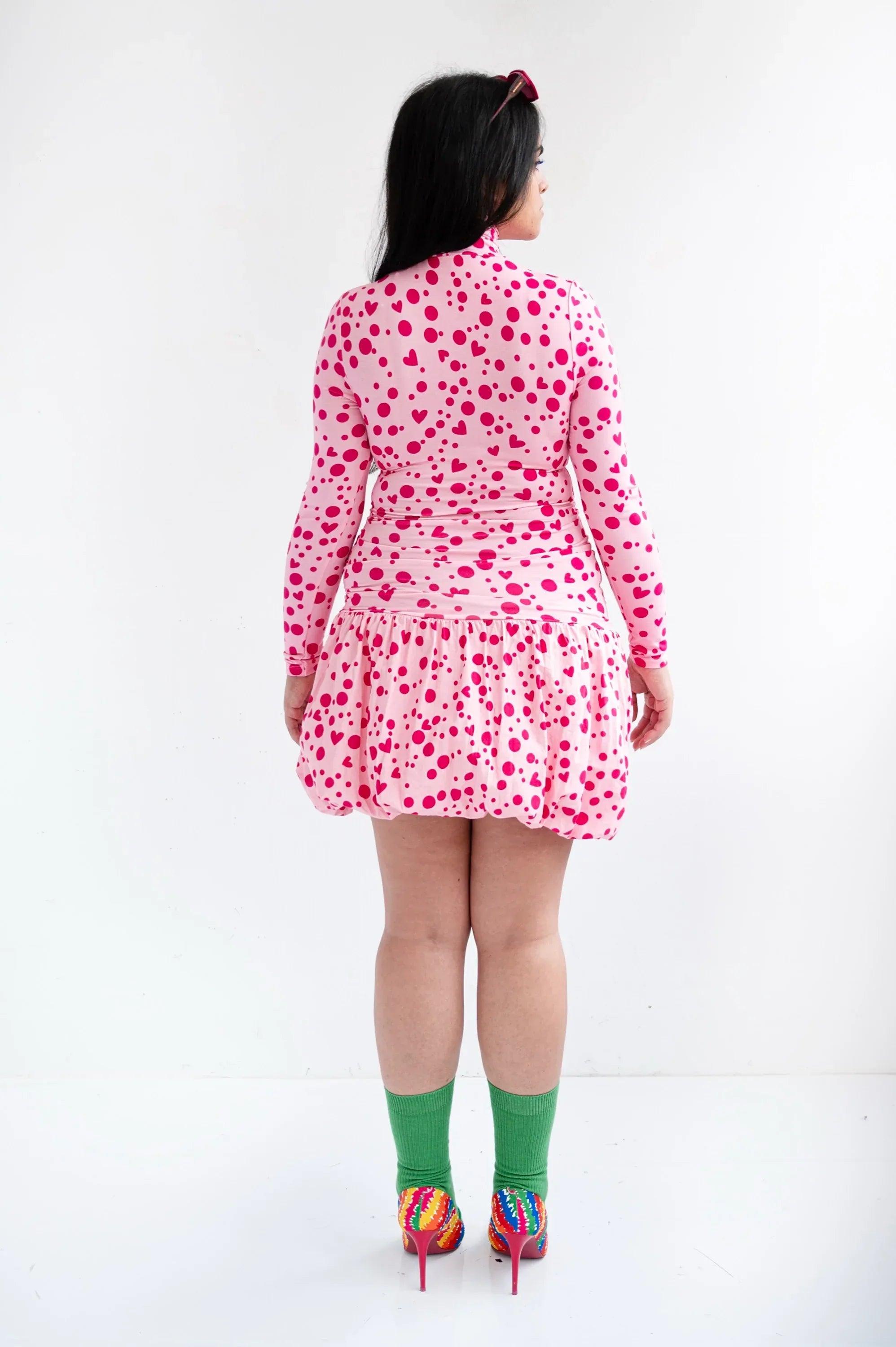 Vestido corto rosa con corazones, vista trasera, cuello alto y manga larga con volantes