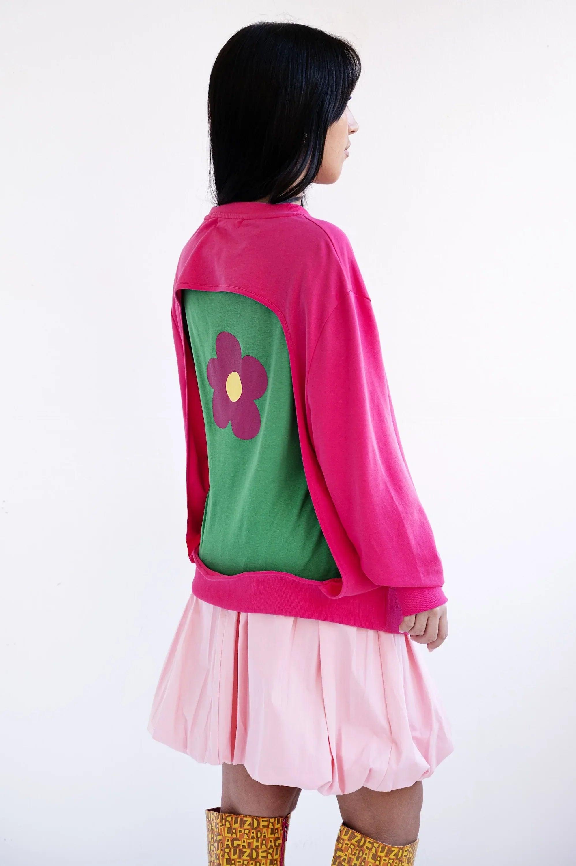 Sudadera fucsia con espalda abierta y panel verde con flor morada.