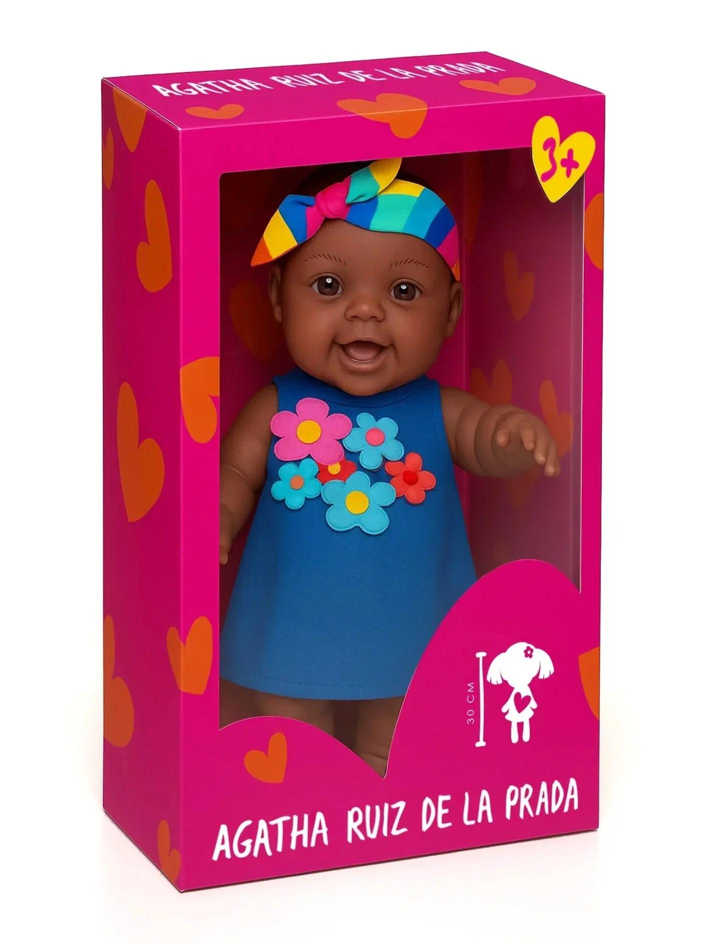 Muñeca en caja con vestido azul sin mangas y flores de colores, diadema multicolor