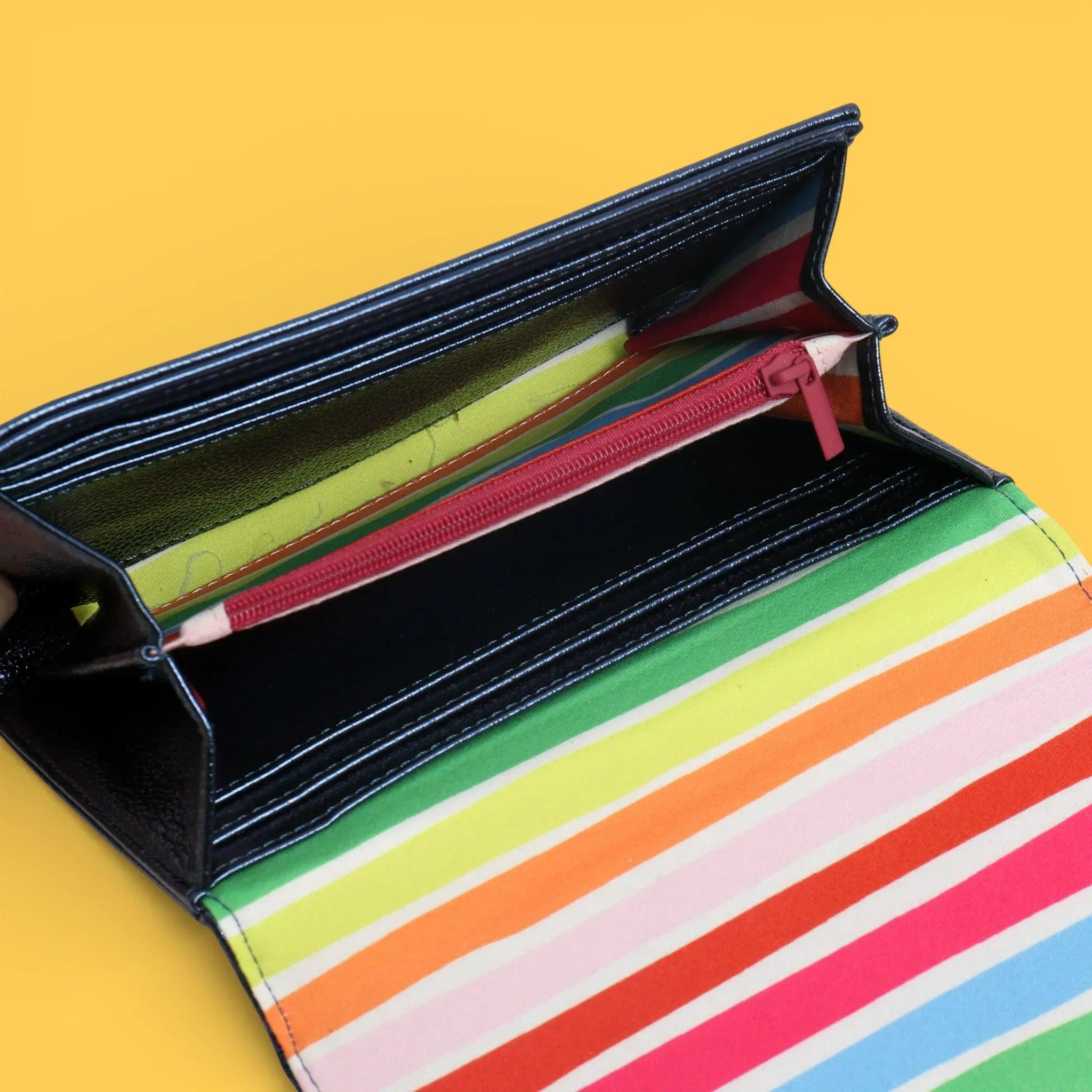 Monedero abierto con forro negro y rayas multicolor en el interior