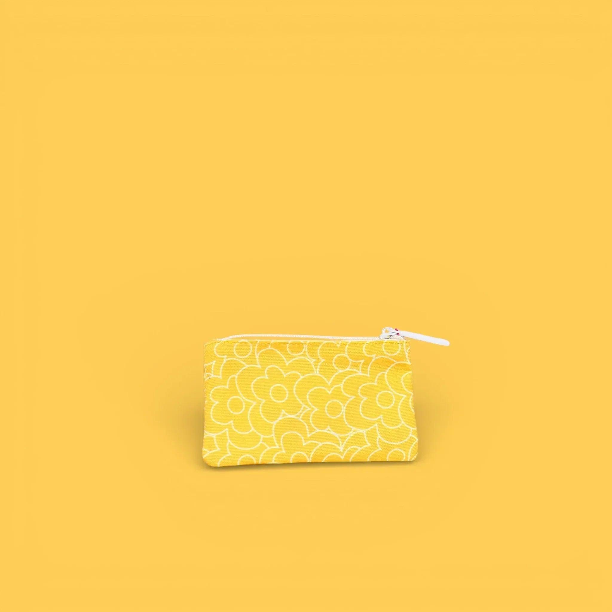 Monedero estampado amarillo con cremallera blanca y dibujos continuos.