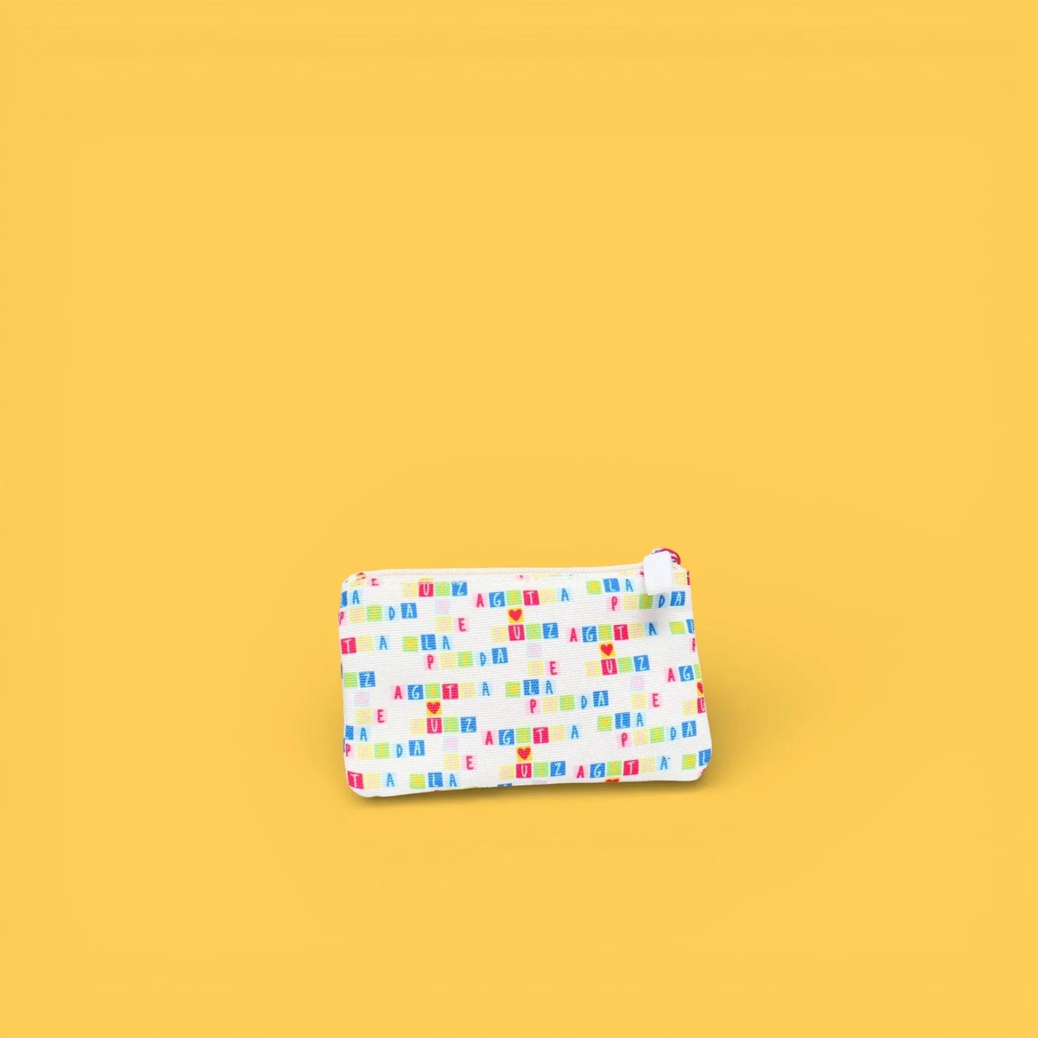 Monedero estampado con cremallera, patrón multicolor sobre tela clara, vista lateral.