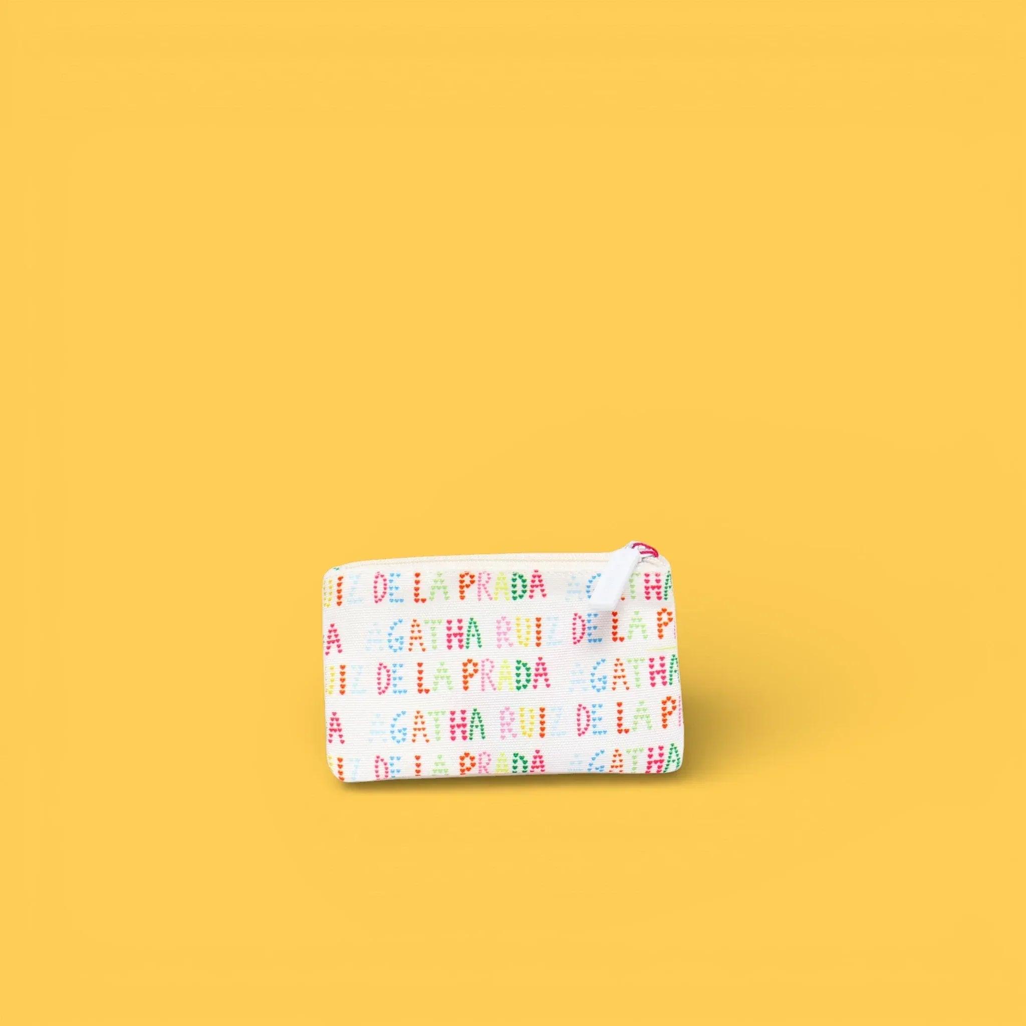 Monedero estampado blanco con cremallera y letras repetidas.