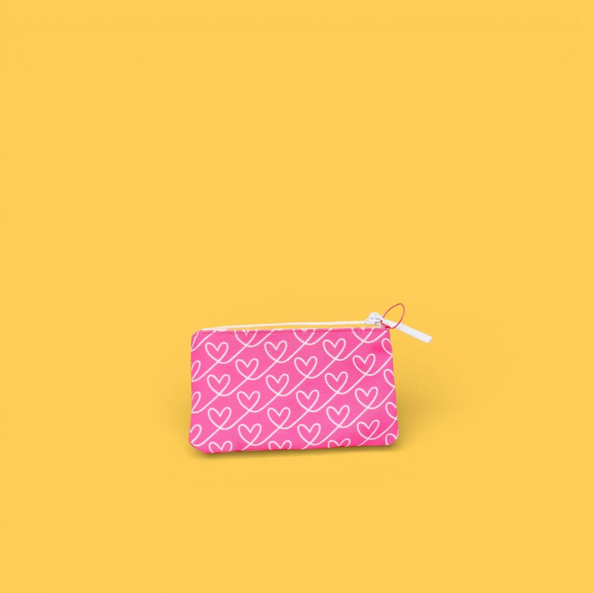Monedero estampado con cremallera rosa con corazones blancos, vista frontal.
