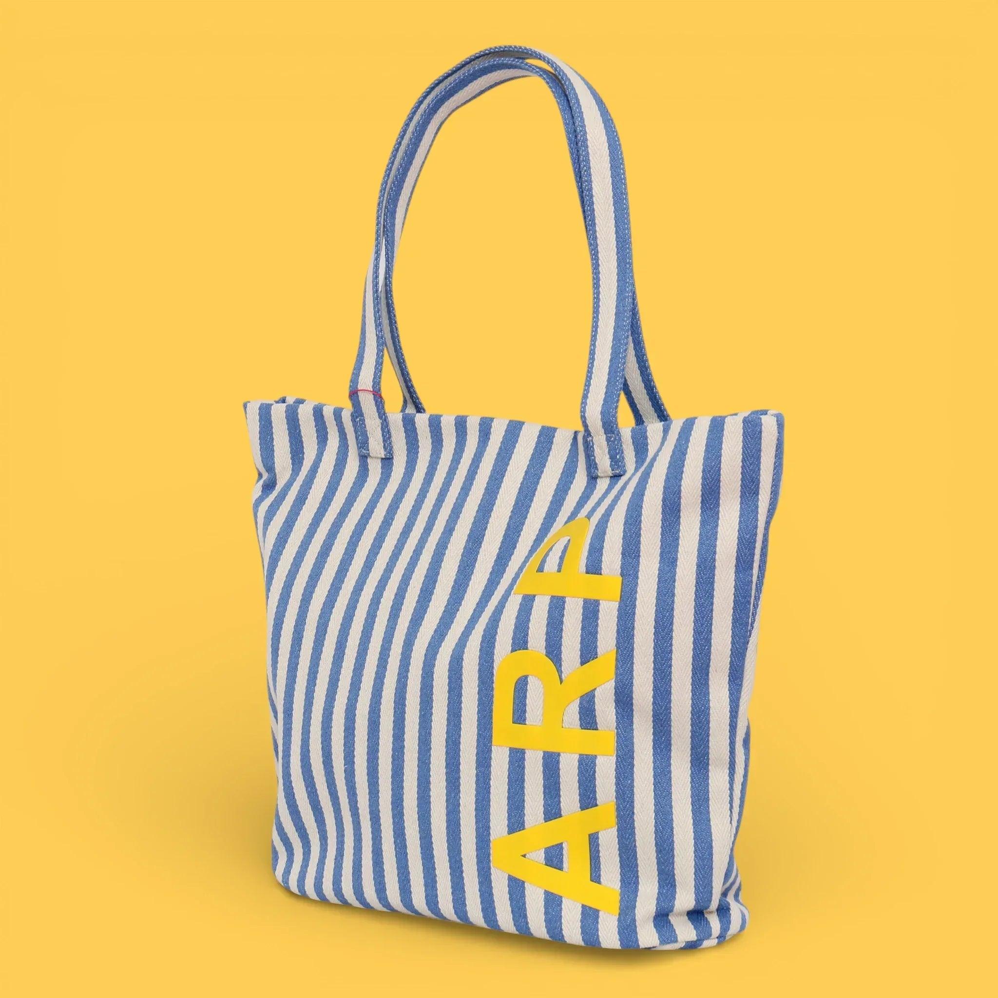 Bolso tote de rayas azul y blancas con asas y estampado de letras amarillas