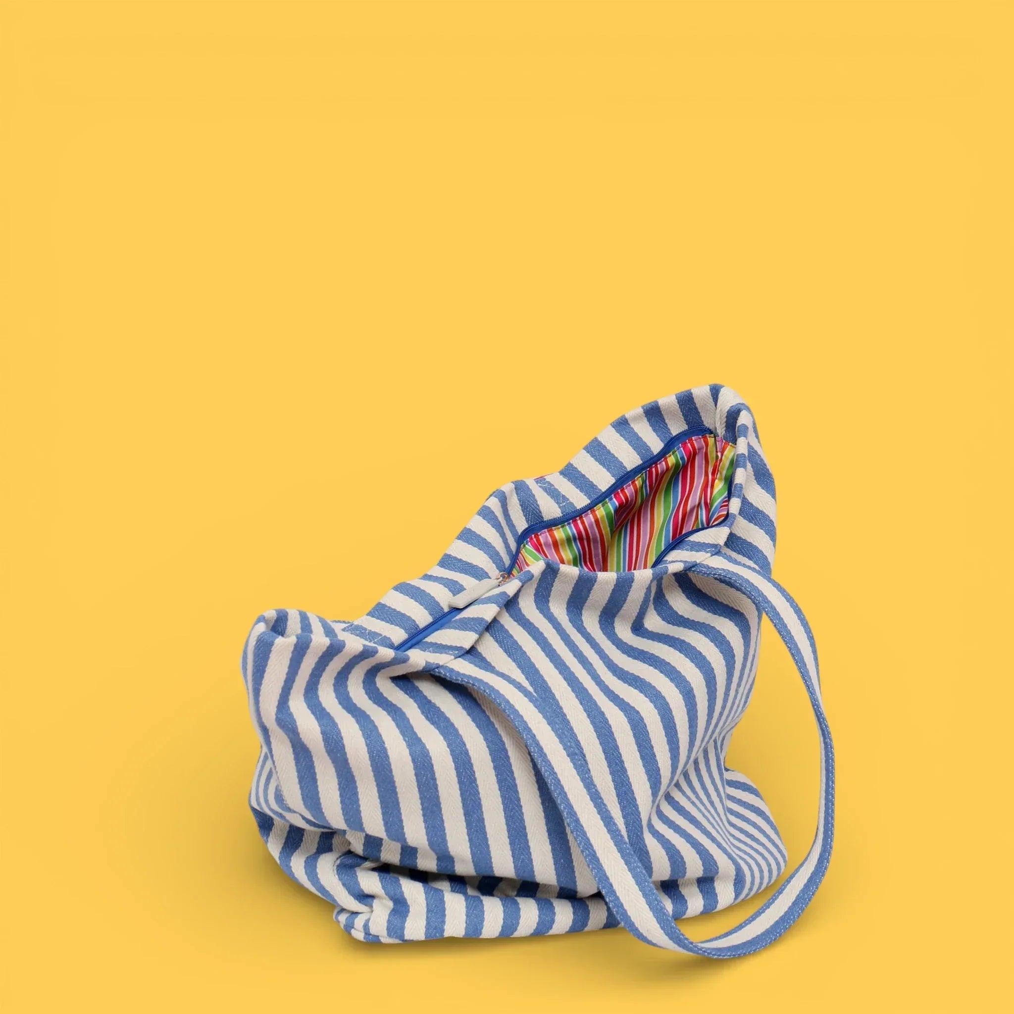 Bolso tote plegado de rayas azul y blancas con interior multicolor visible