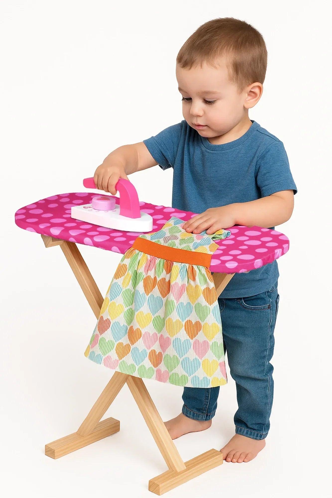 Tabla de planchar infantil rosa de lunares con plancha y prenda multicolor sobre la mesa