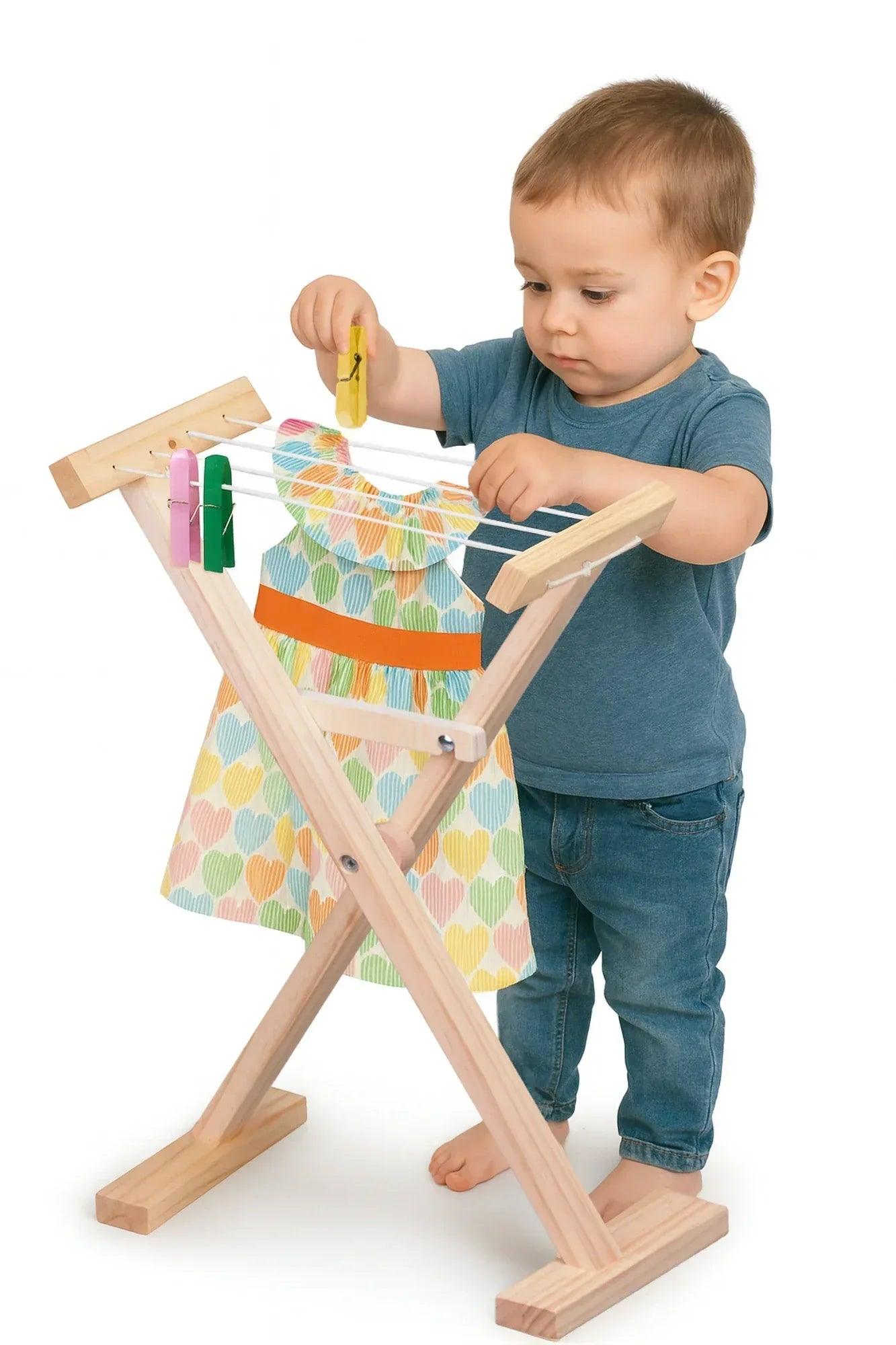 Tabla de planchar infantil de madera con plancha rosa y prenda de colores en el soporte