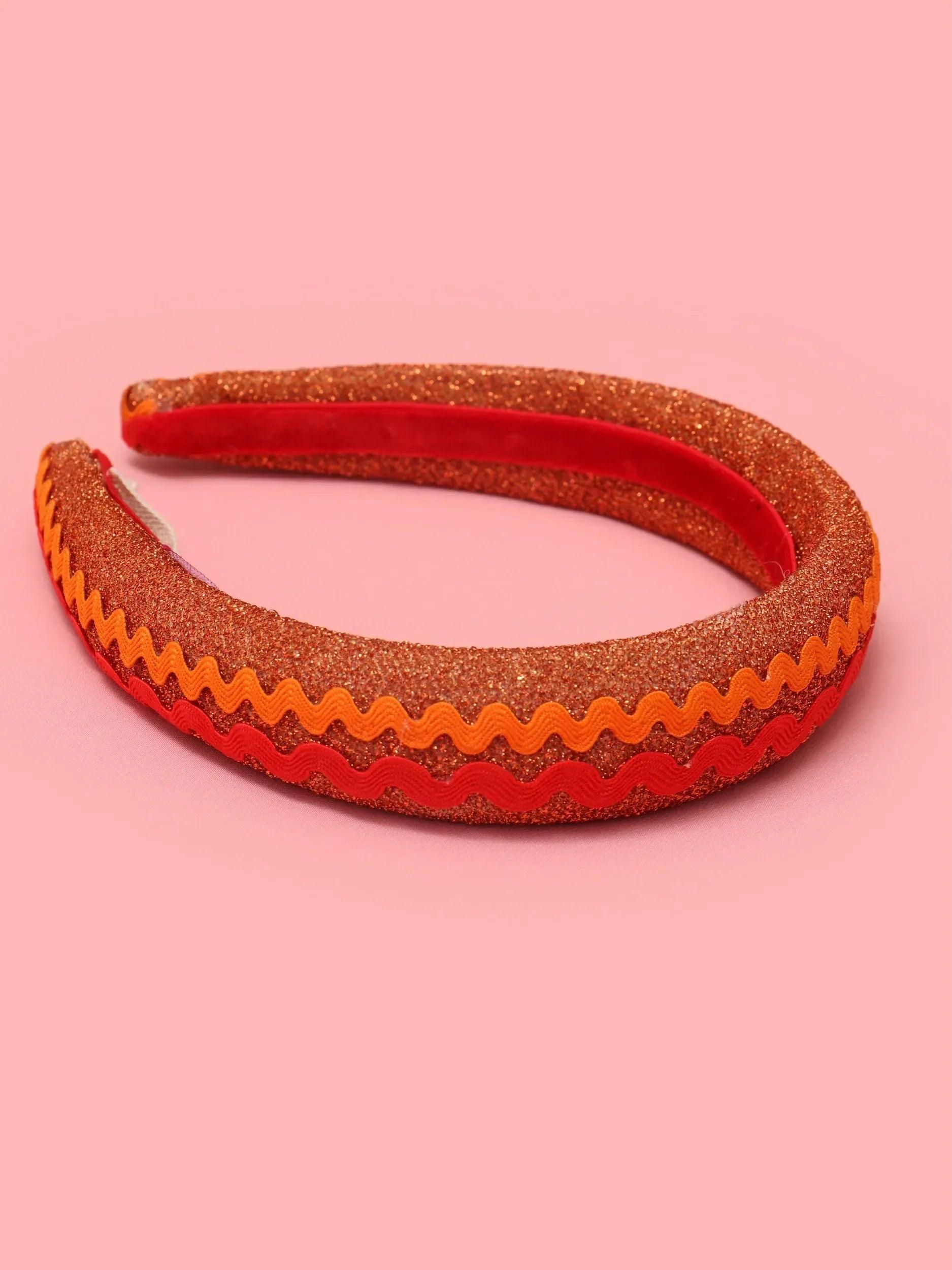 Diadema de tela con patrón zigzag rojo y naranja, con franja interior marrón