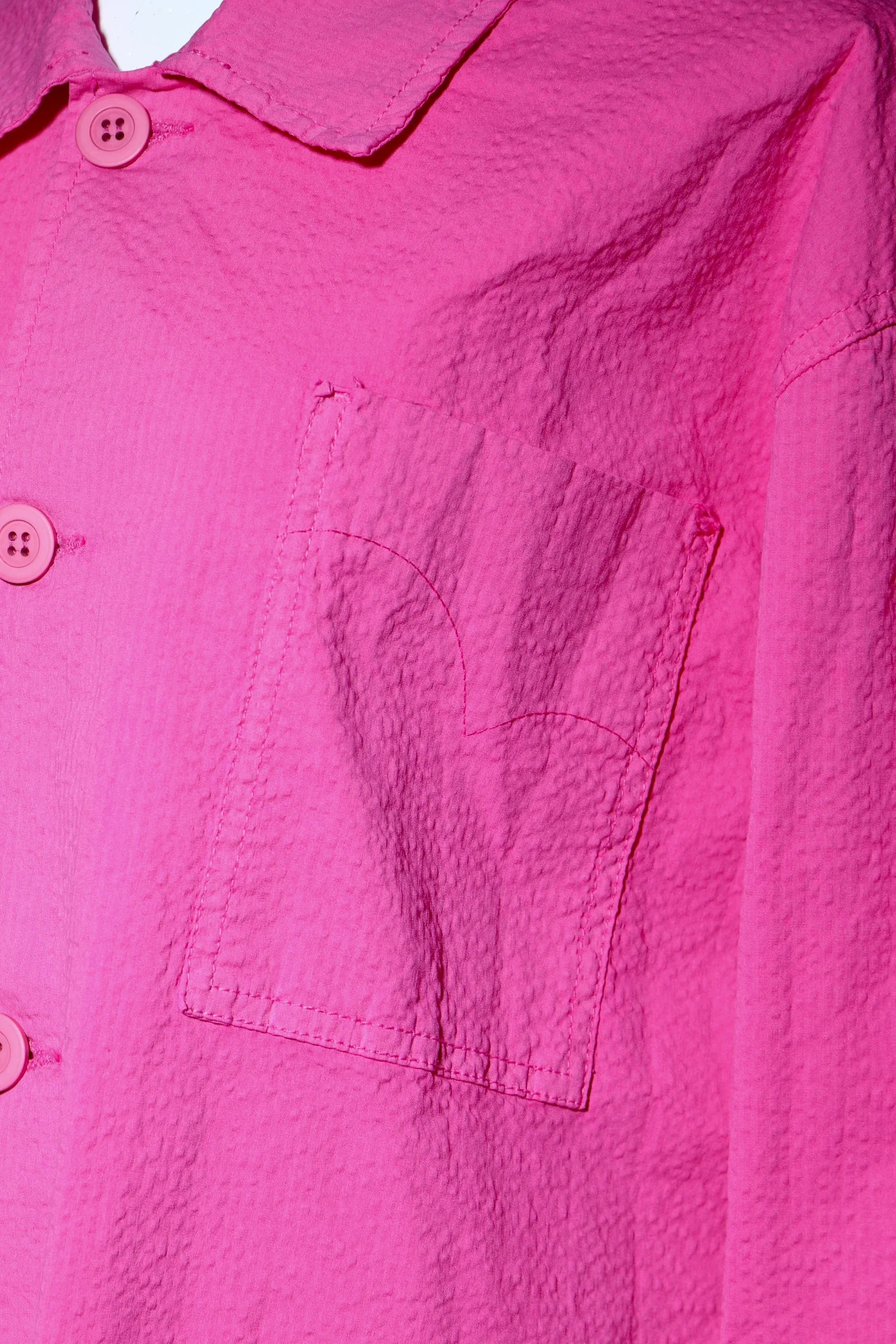 Sobrecamisa fucsia: botones delanteros y bolsillo con costuras visibles
