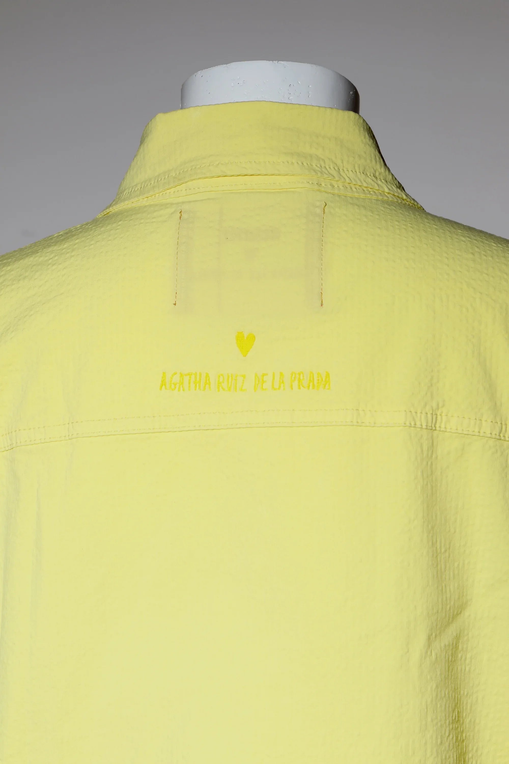 Sobrecamisa amarilla con etiqueta en la espalda, vista posterior cercana