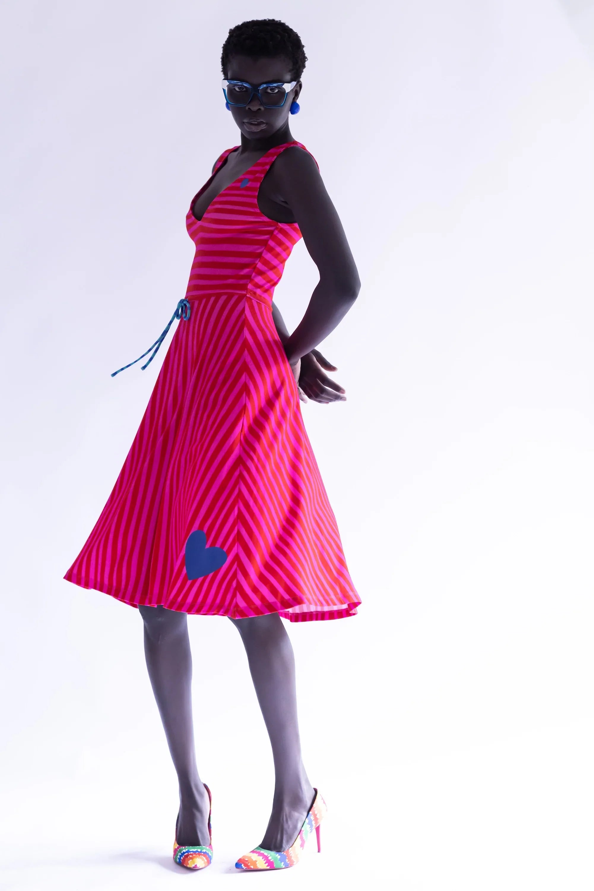 Vestido sin mangas rayado fucsia y rojo, falda plisada y corazón en el bajo.