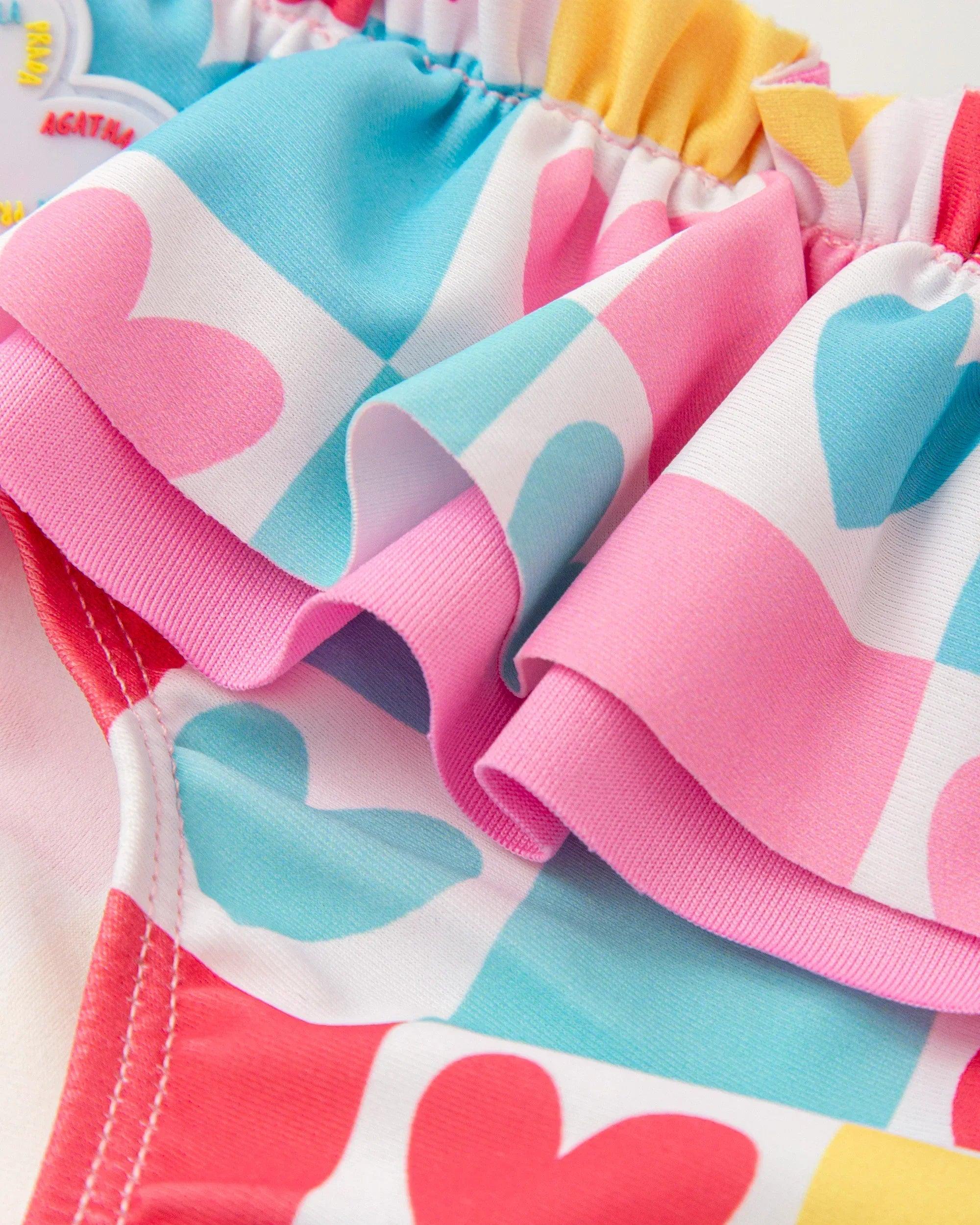 Detalle de bikini licra con volante estampado de corazones rosa, azul y amarillo