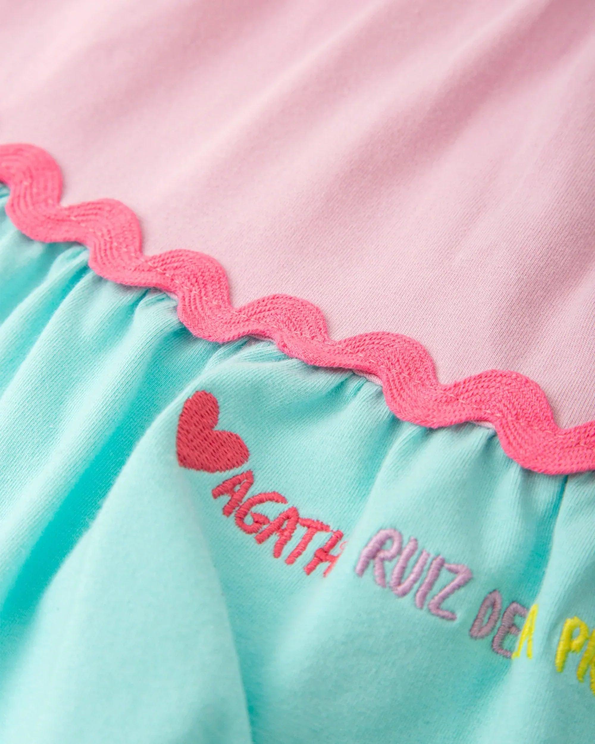 Volante de picunela del vestido: franja rosa y turquesa con bordado decorativo.