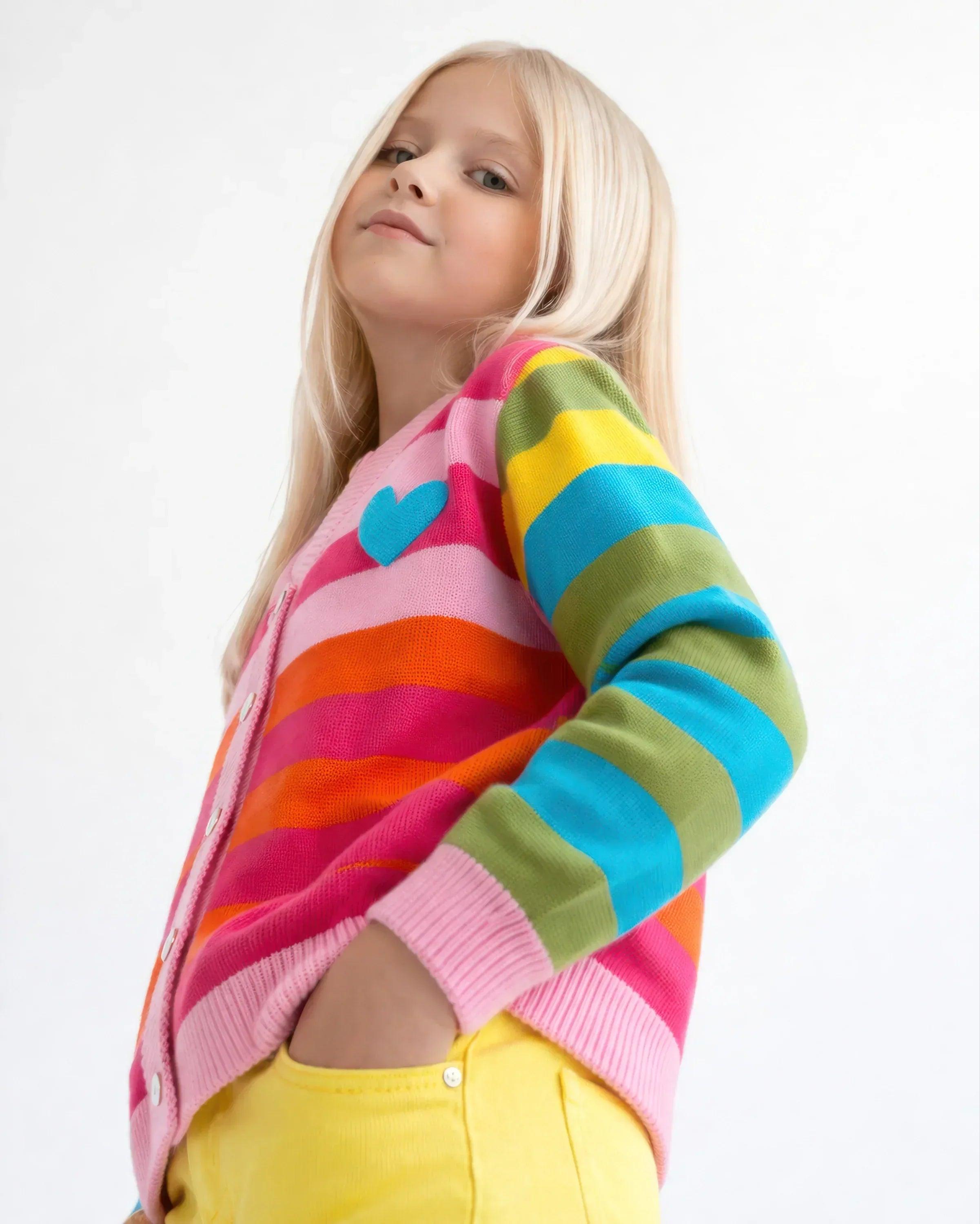 Chaqueta infantil de punto con rayas arcoíris, vista lateral, rosa con puños acanalados.